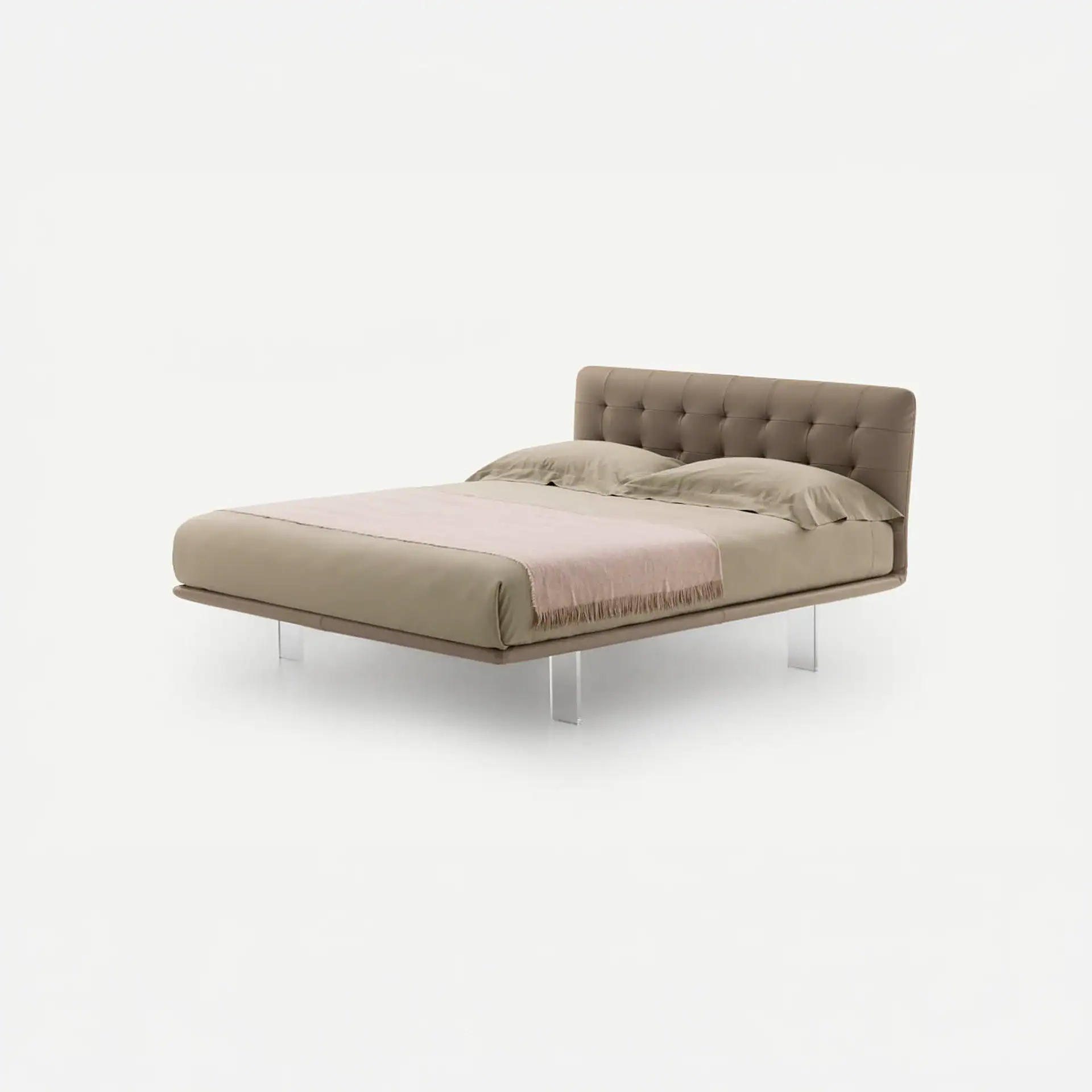 A modern bed with a tufted taupe headboard, taupe bedding, a pink throw blanket, and clear acrylic legs, set against a white background.