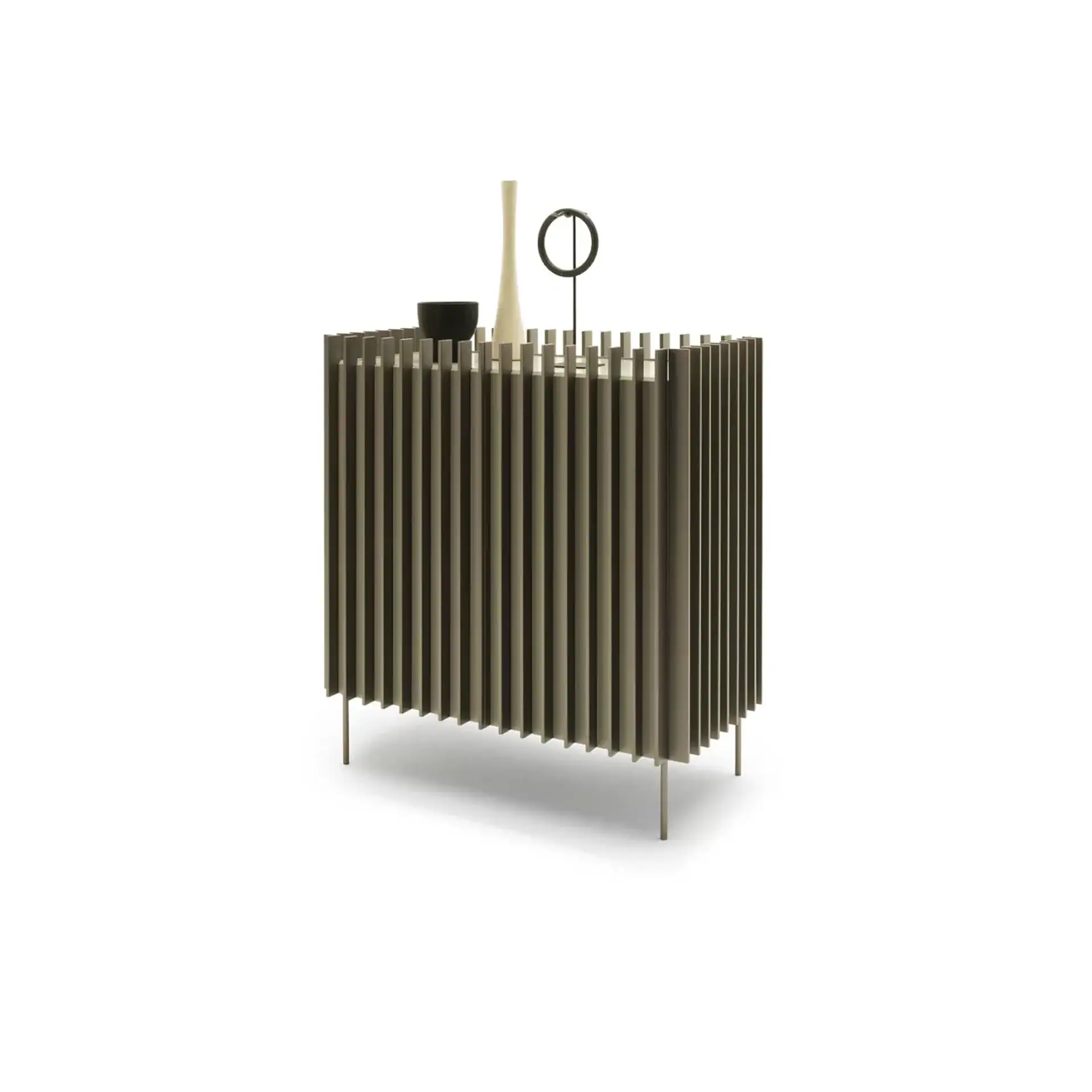 A modern, rectangular cabinet with vertical slats in a muted olive-green color, featuring a black bowl, a cream vase, and a black abstract sculpture on its top surface, all against a white background.