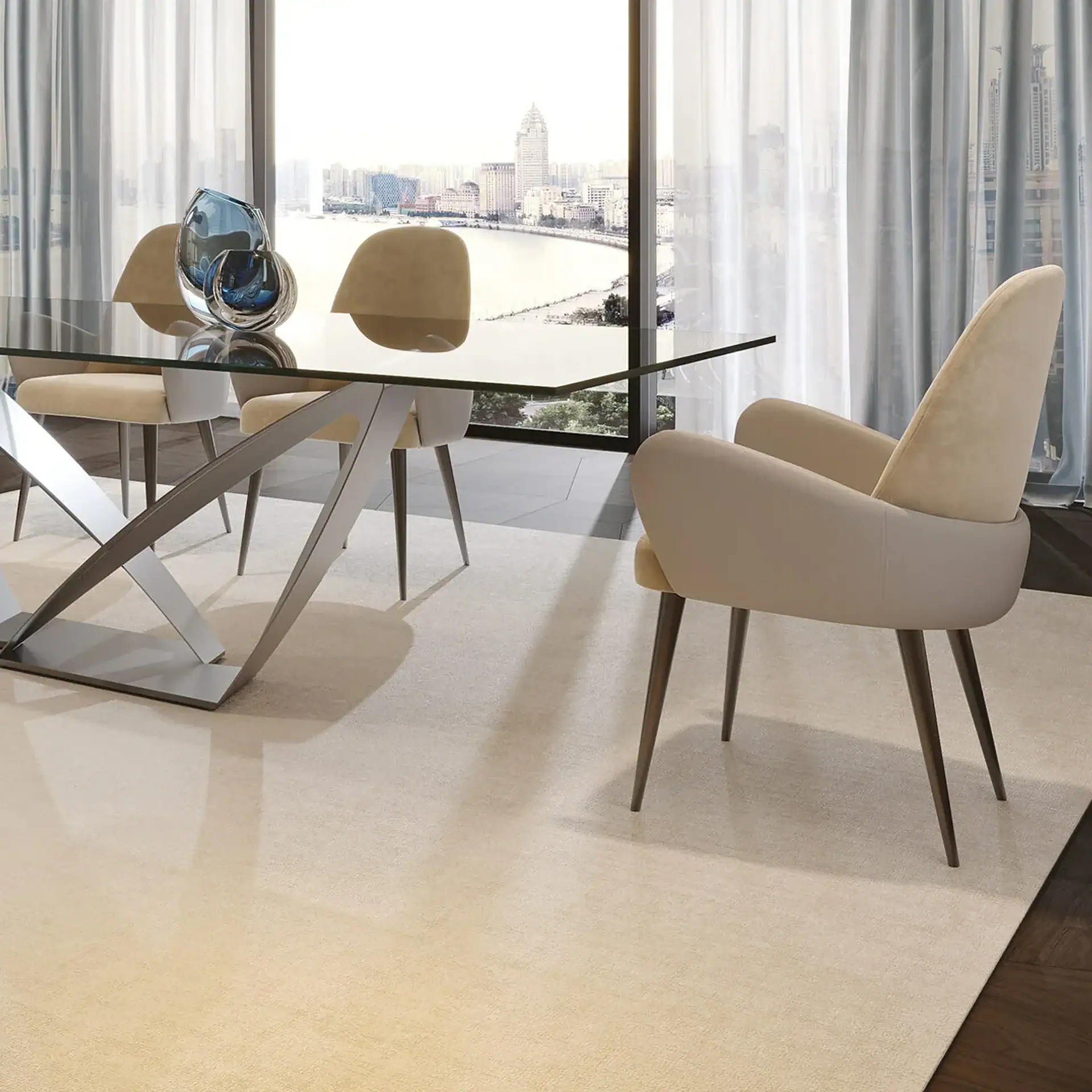 A modern dining room with a glass table, beige chairs, and blue vases, set against a large window with a city and river view.