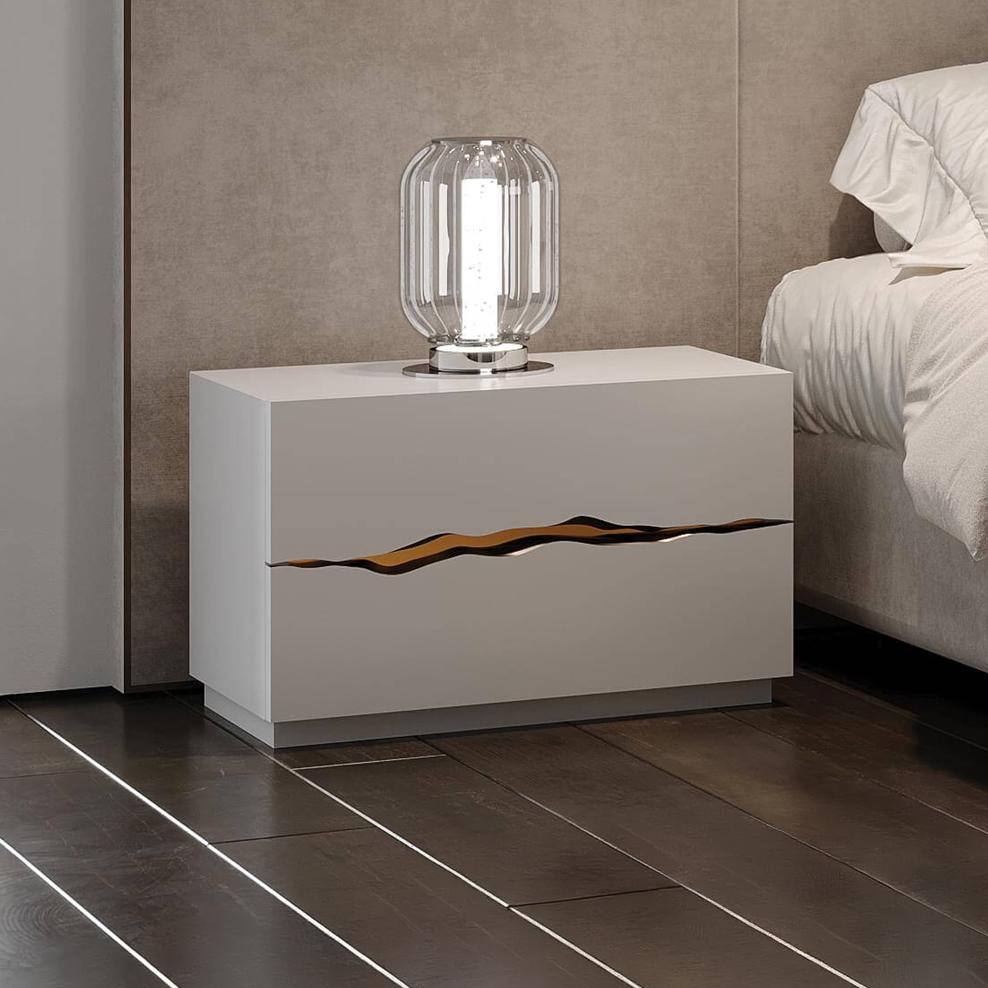 A modern light gray nightstand with a unique golden 'crack' design on its front, topped by a fluted glass lamp, next to a bed with white bedding in a contemporary bedroom.