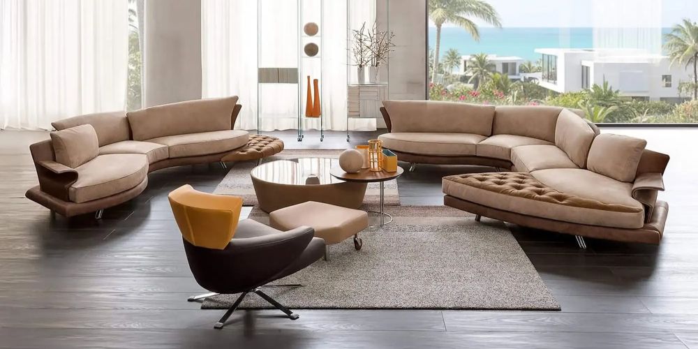 Modern living room with curved beige sofas, a yellow armchair, and a large window overlooking a tropical ocean with palm trees and white buildings. Super Roy Curved Modular Sofa by IL Loft