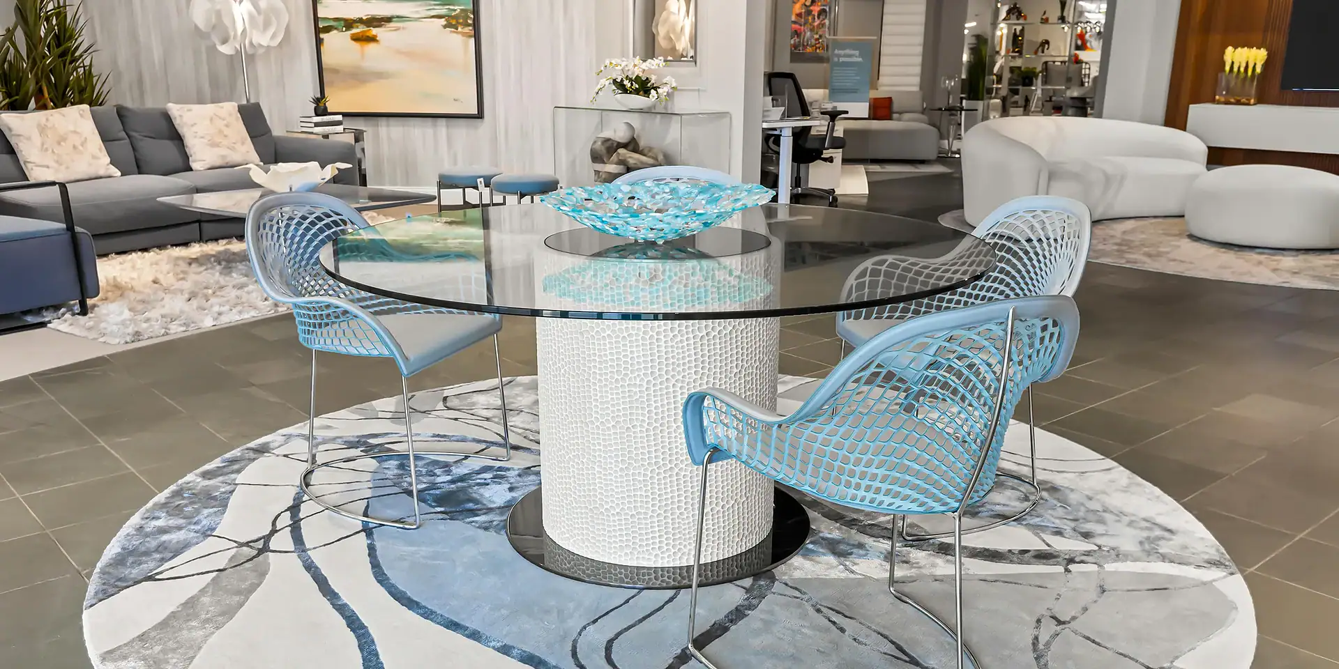 Stylish glass dining table with blue woven chairs in contemporary living space.