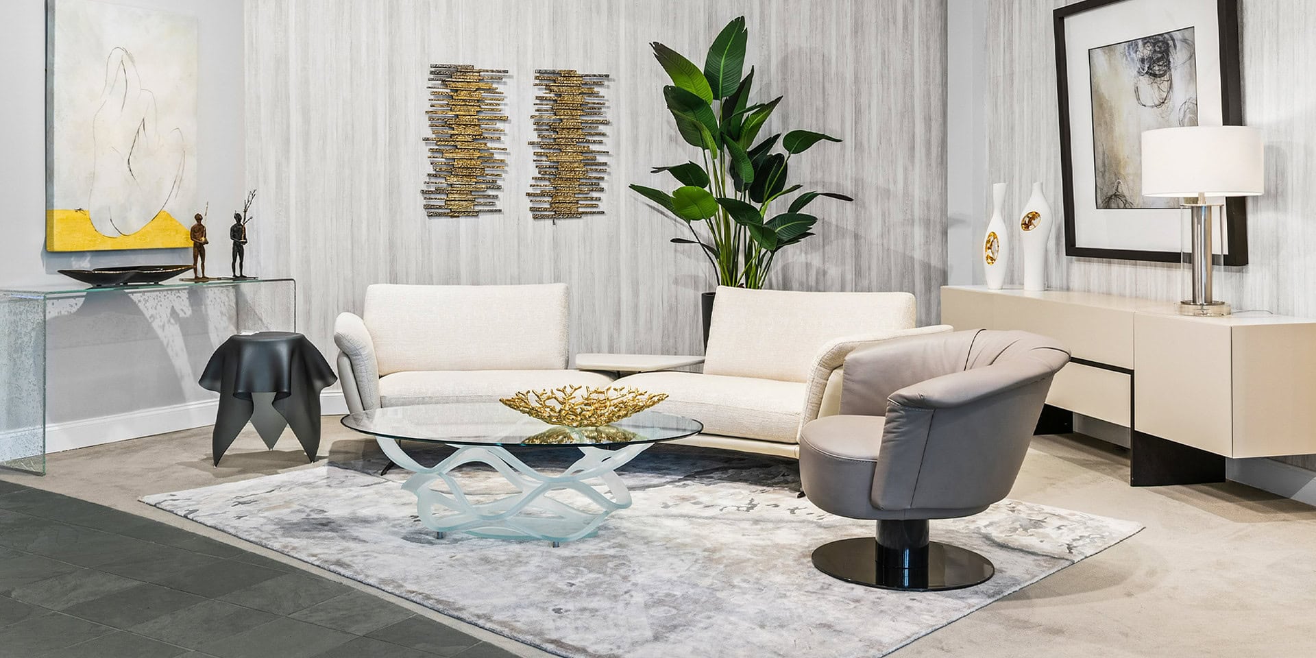 Elegant living room featuring contemporary sofas, a glass coffee table, and stylish decor accents. P.