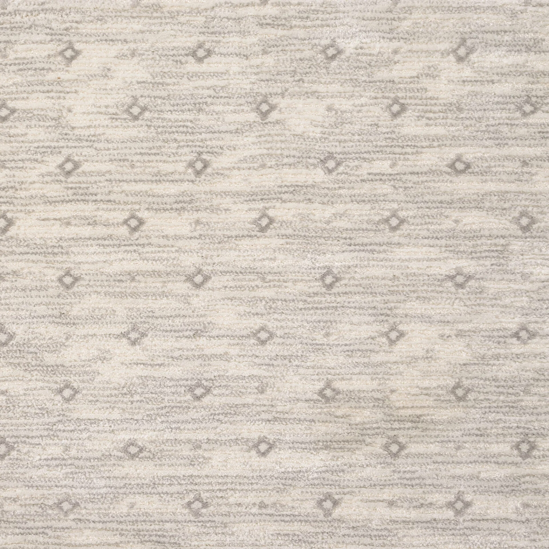 Close-up of a cream and light gray textured rug with horizontal stripes and scattered small gray diamond patterns.