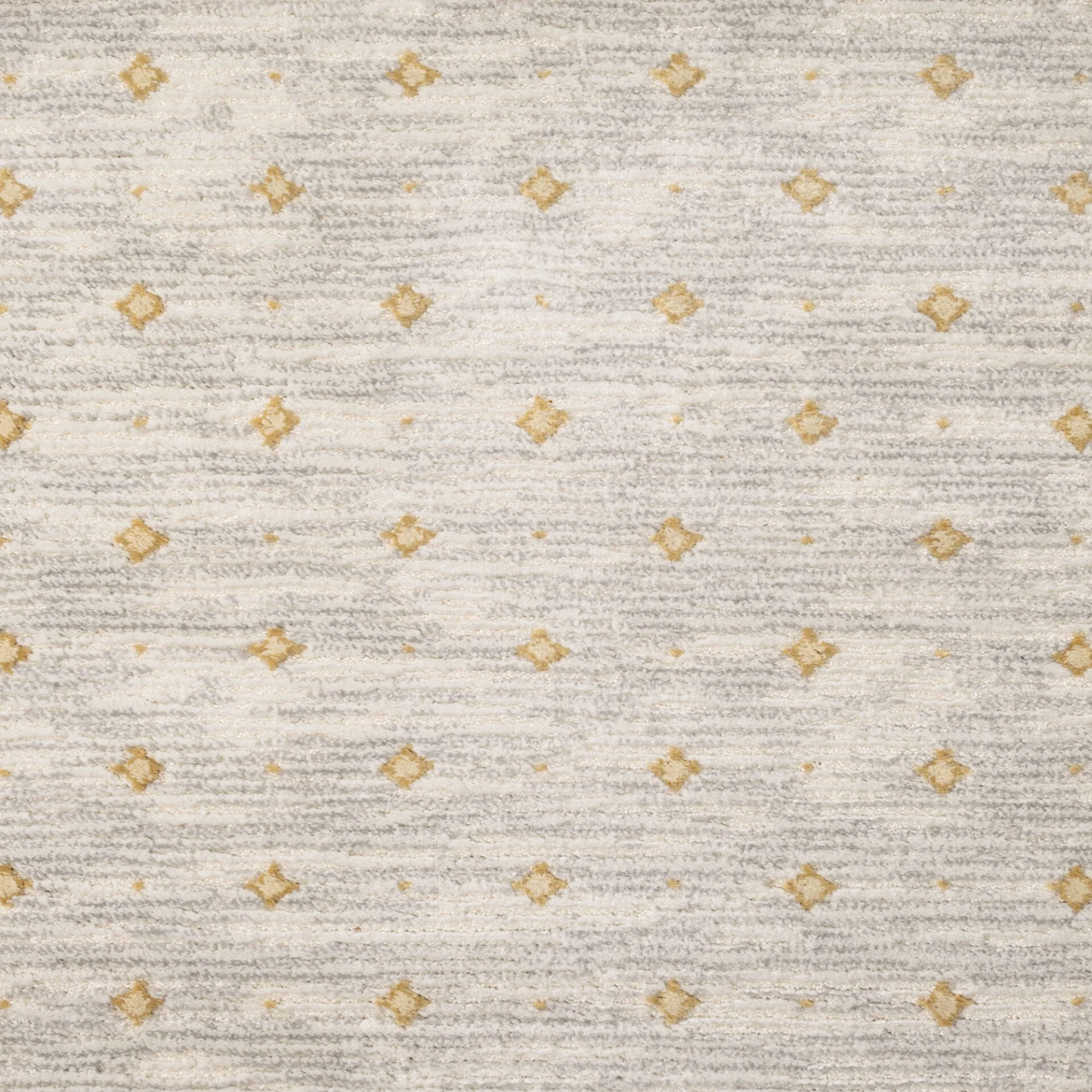 Close-up of a textured carpet with a pattern of muted gold diamonds and small dots on an off-white and light grey striped background.