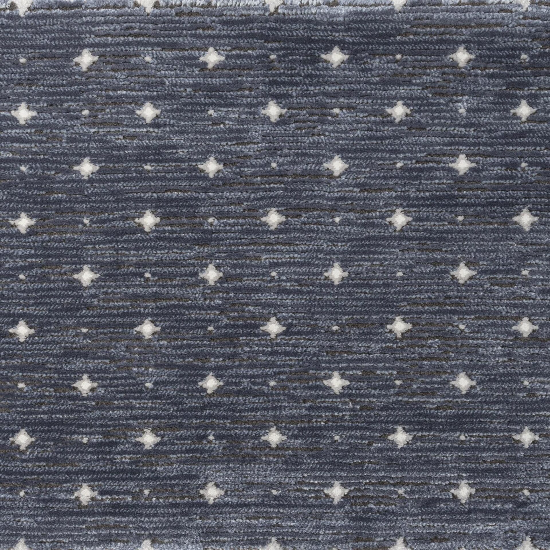 Close-up of a dark blue-grey textured carpet with a repeating pattern of small, off-white star shapes.