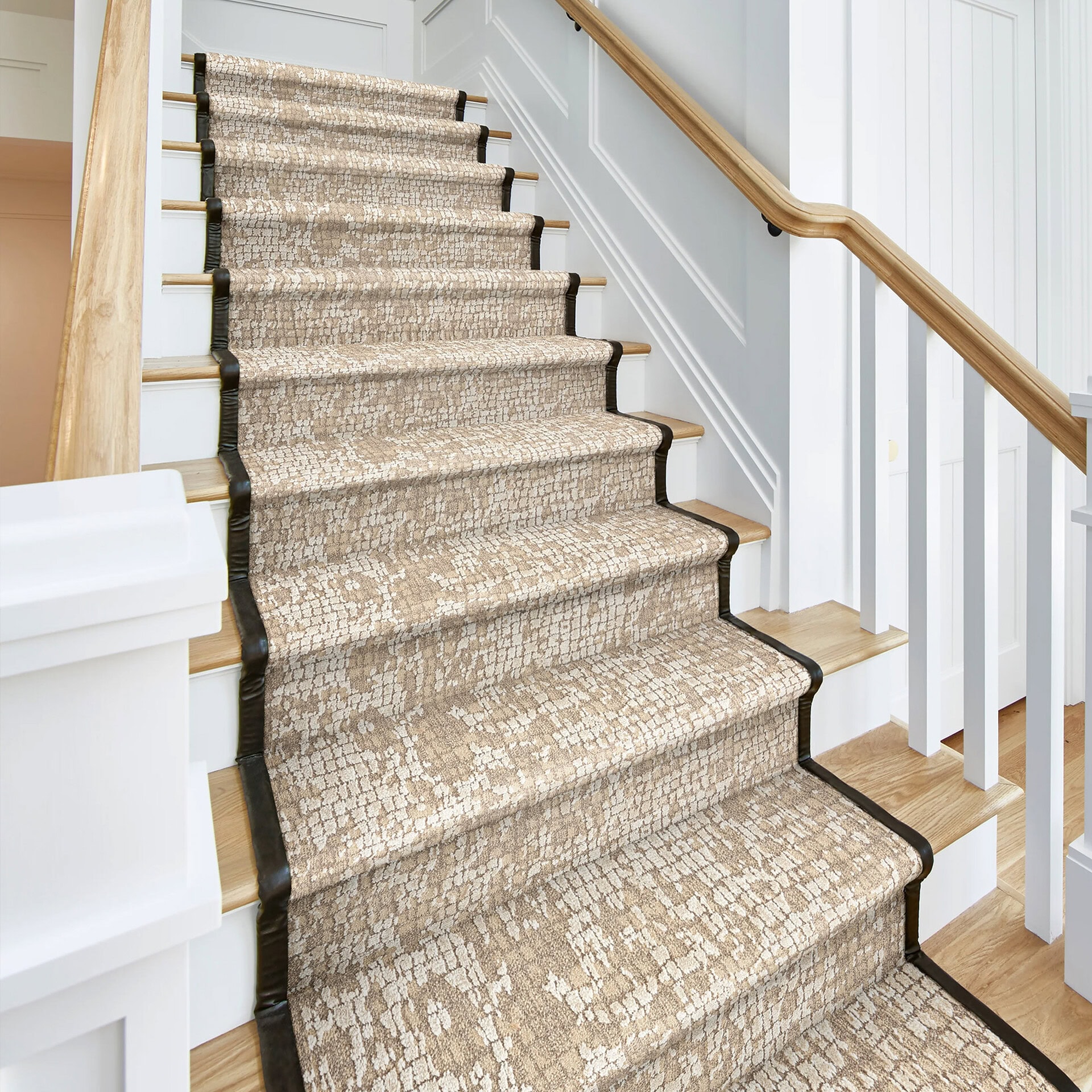 Elegant woven area rug on staircase with neutral tones and black border.