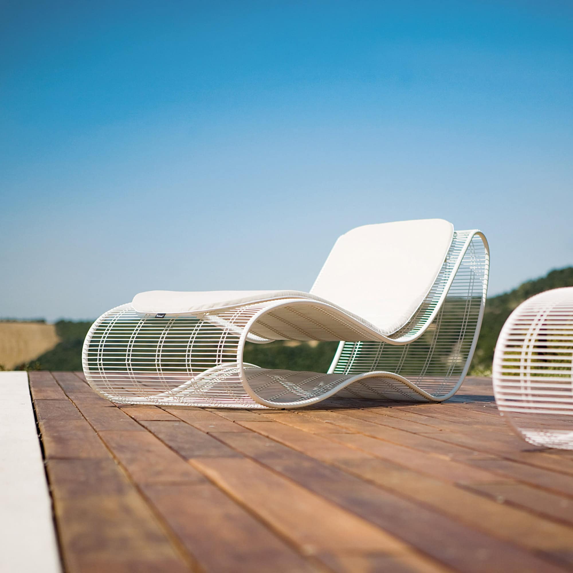 Modern Breez outdoor chaise lounge with sleek metal frame and white cushion.