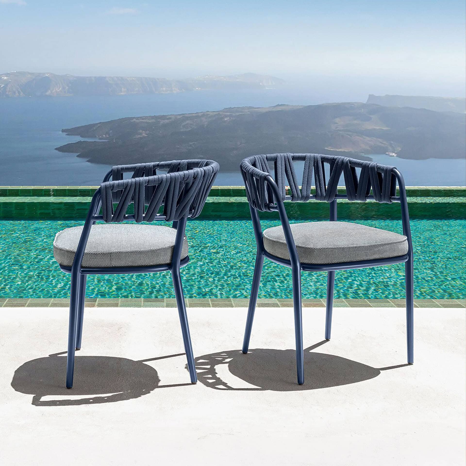 Stylish navy blue outdoor dining chairs with light gray cushions on a terrace.