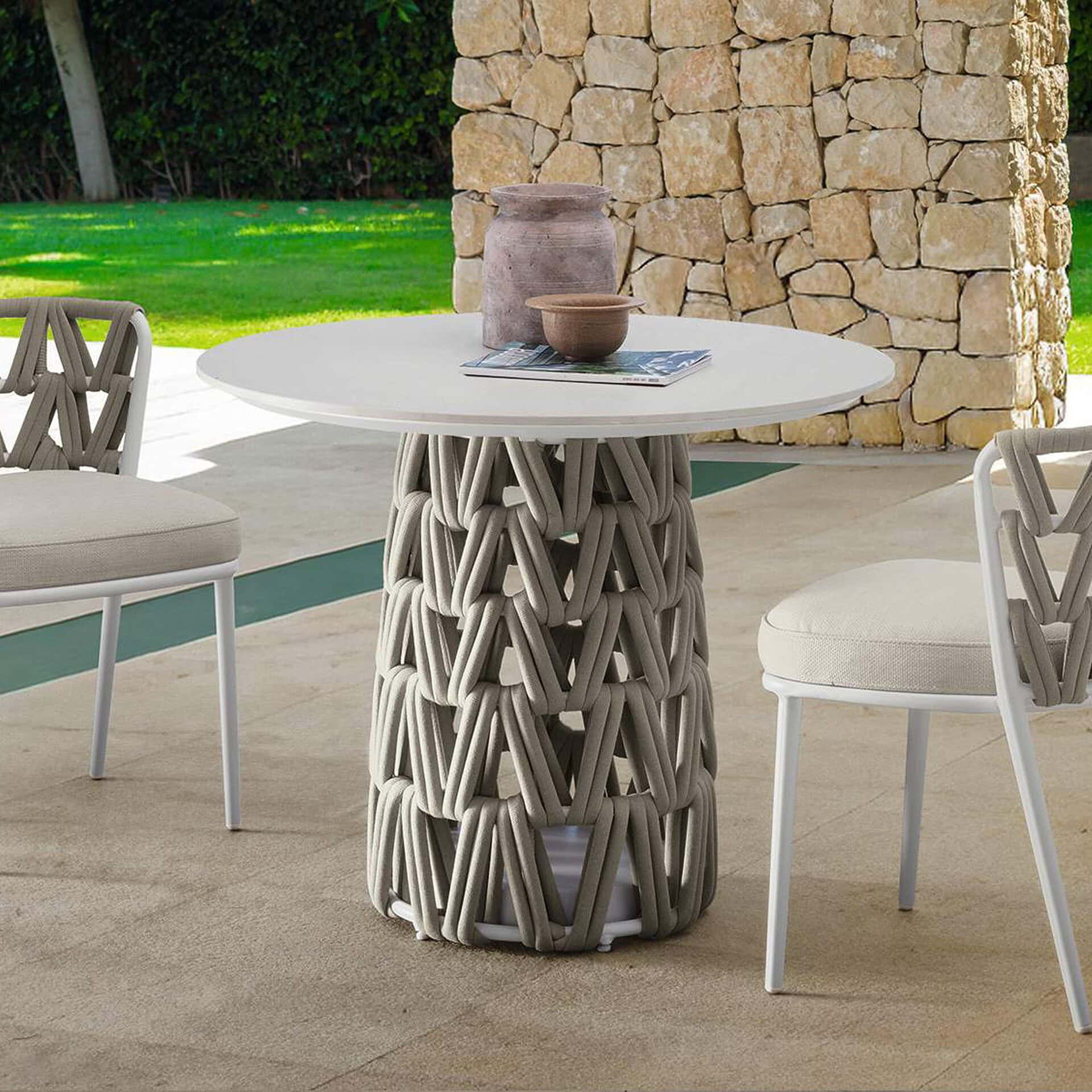 Outdoor dining table with a unique woven base and a round white top. Perfect for patios and outdoor.