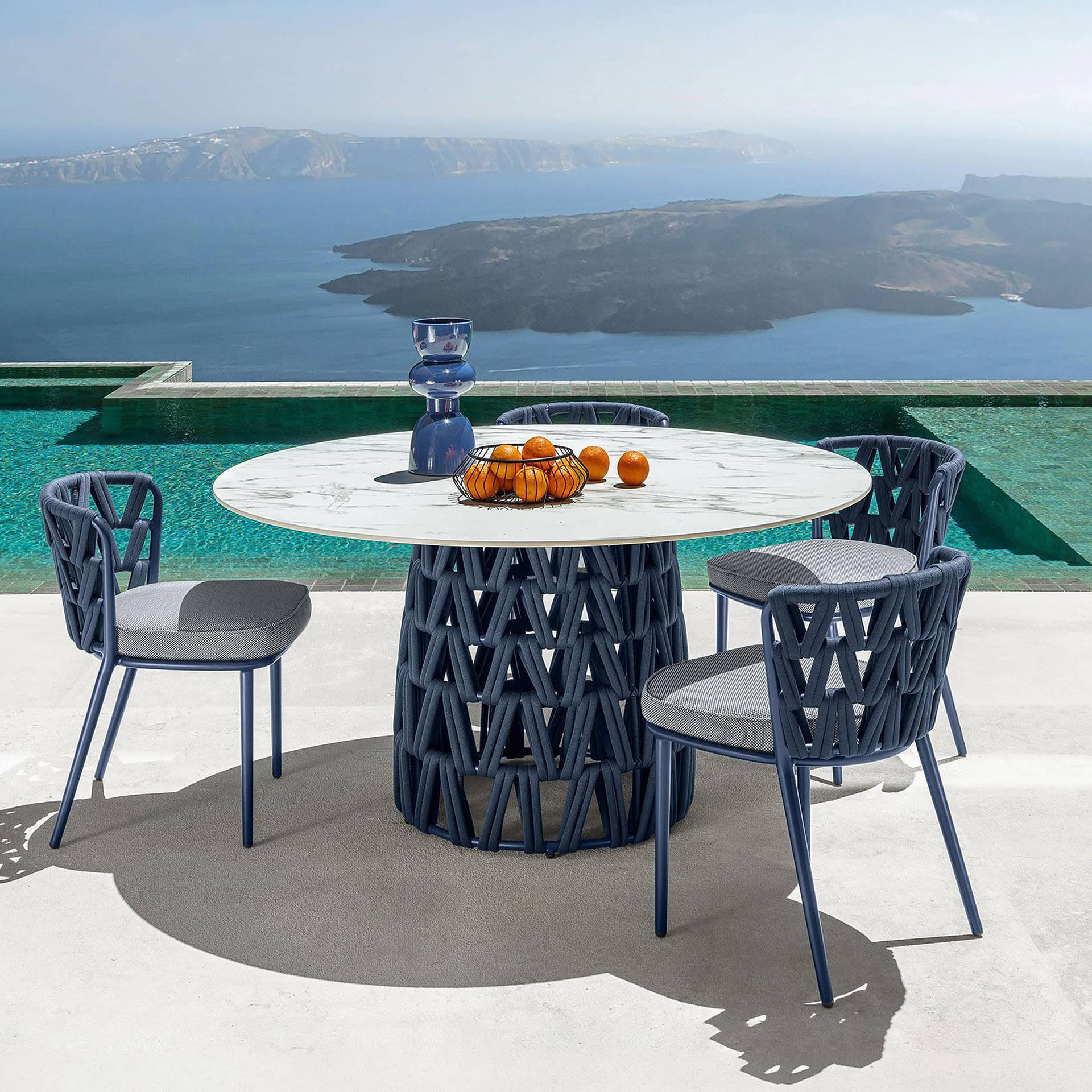Modern outdoor dining table with four stylish chairs by the poolside.