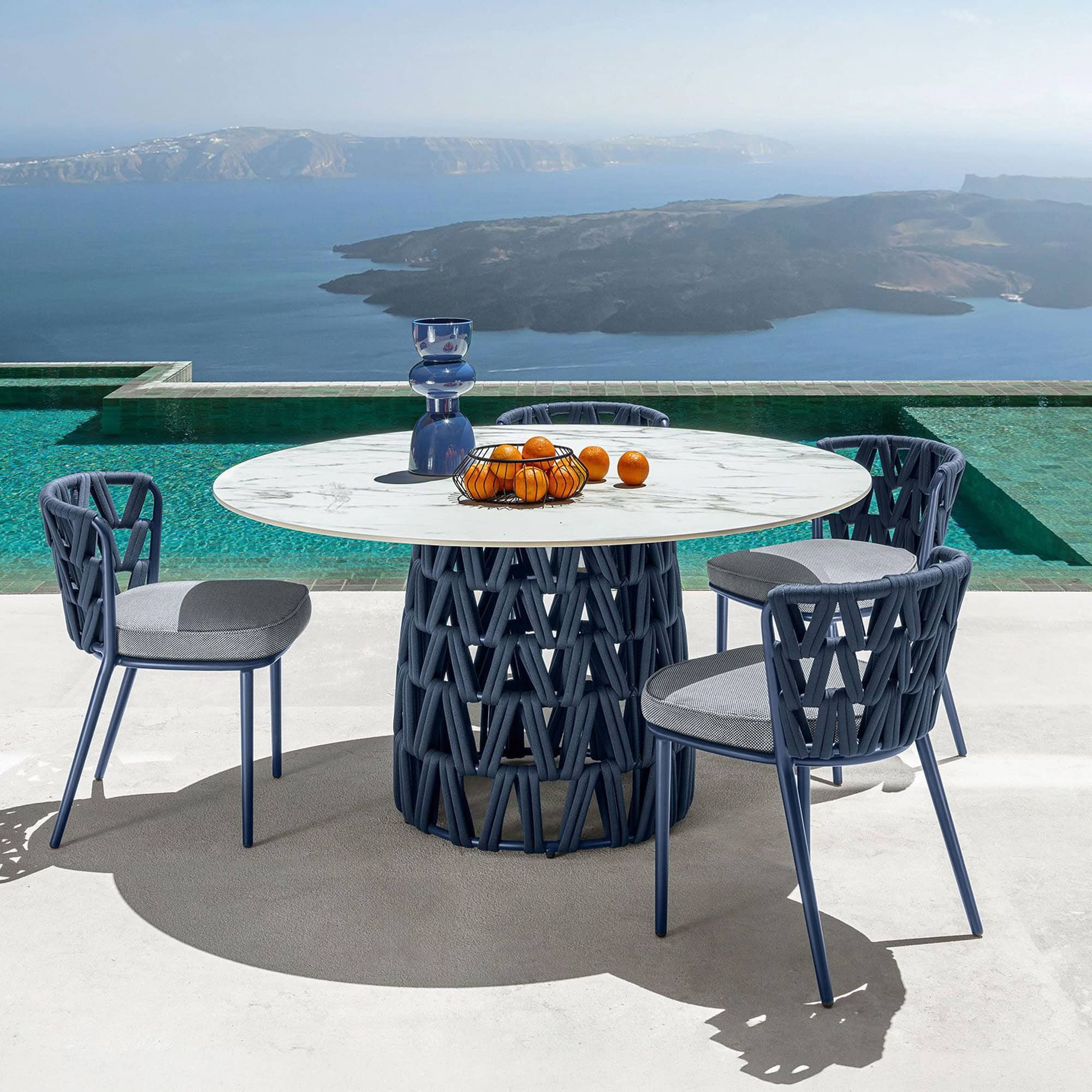 Modern outdoor dining table with four stylish chairs by the poolside.