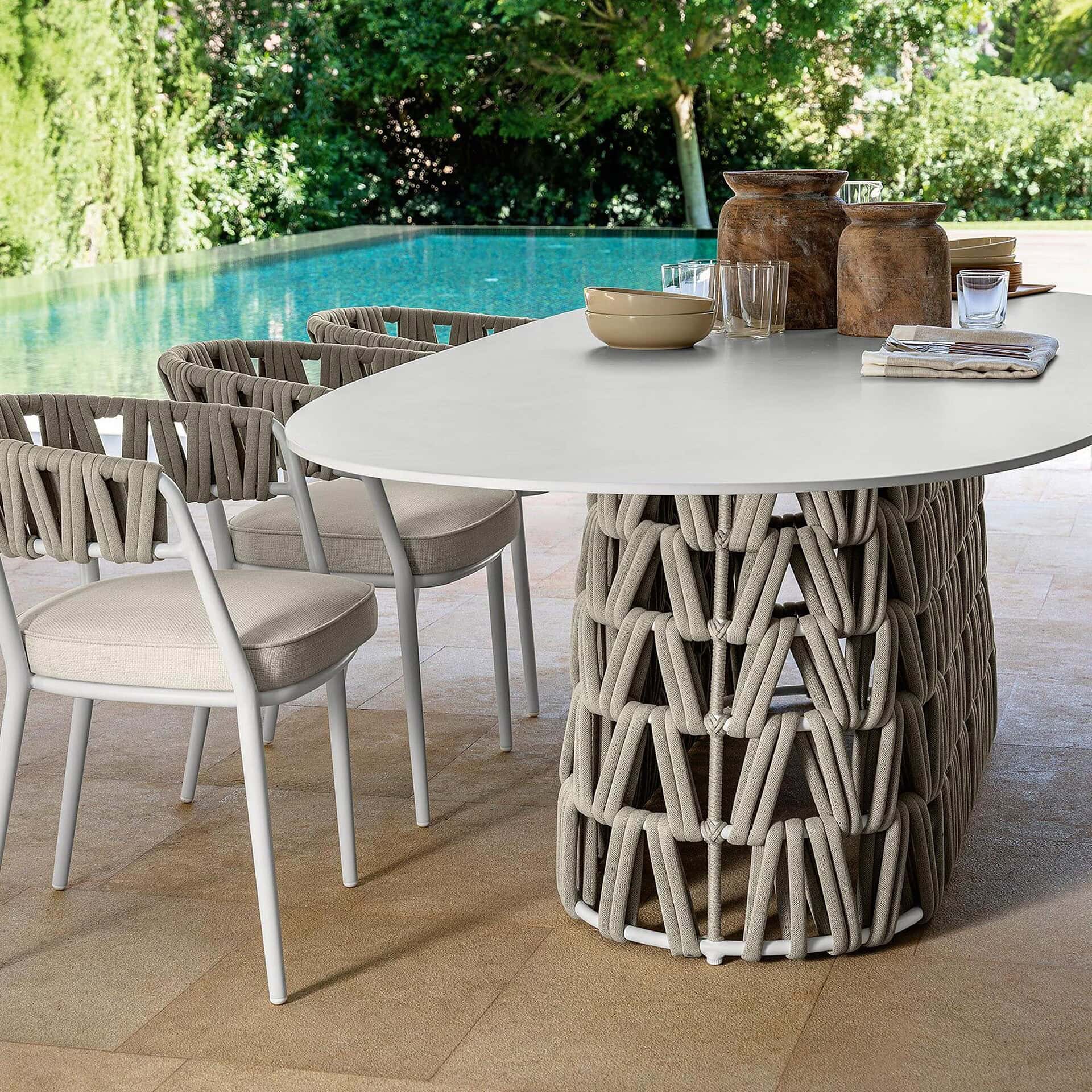 Outdoor dining table with a stylish, woven base and a sleek white top. Perfect for poolside gatherin.