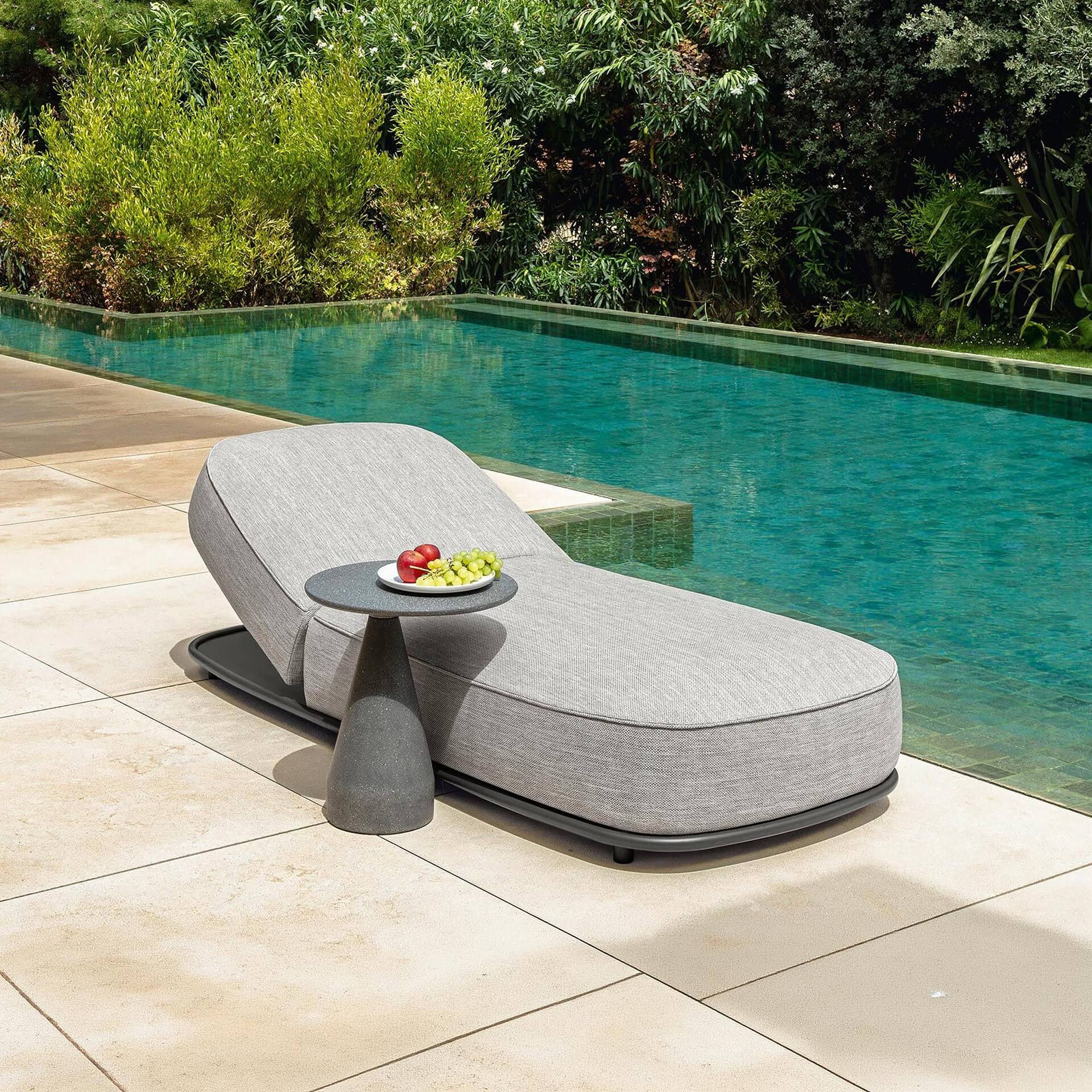 Modern outdoor sunbed with side table by the poolside.
