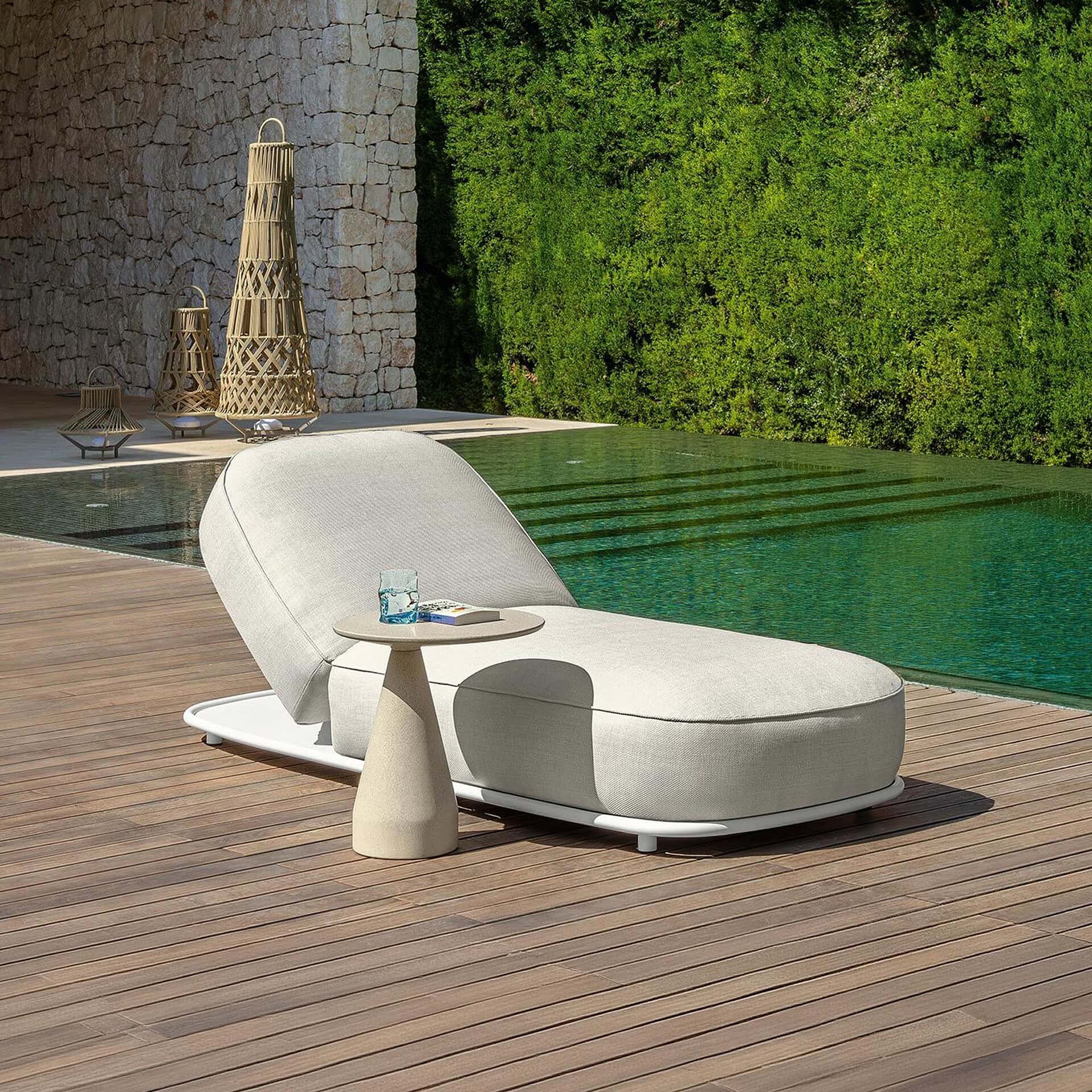 Modern outdoor sunbed on wooden deck near pool.