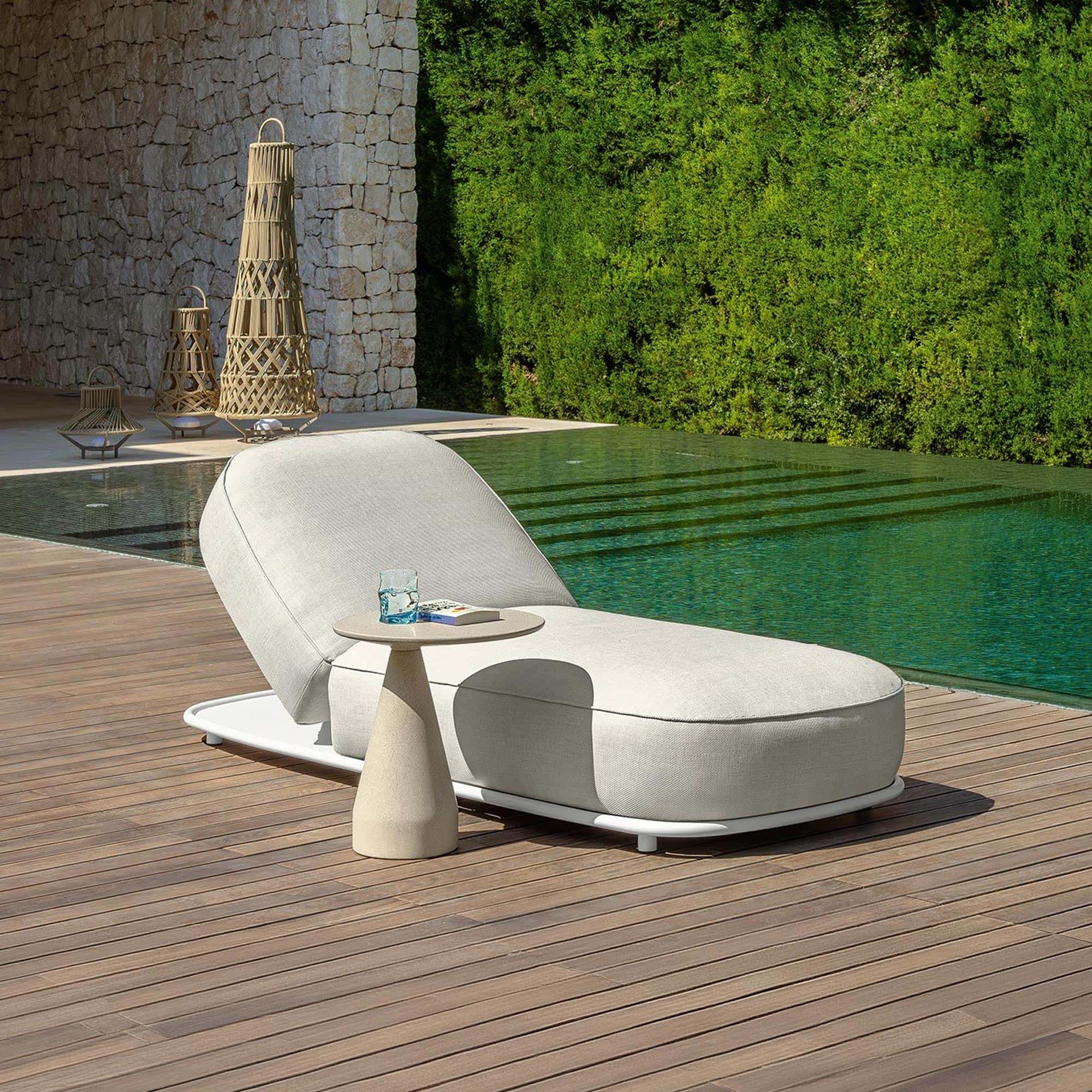 Modern outdoor sunbed on wooden deck near pool.