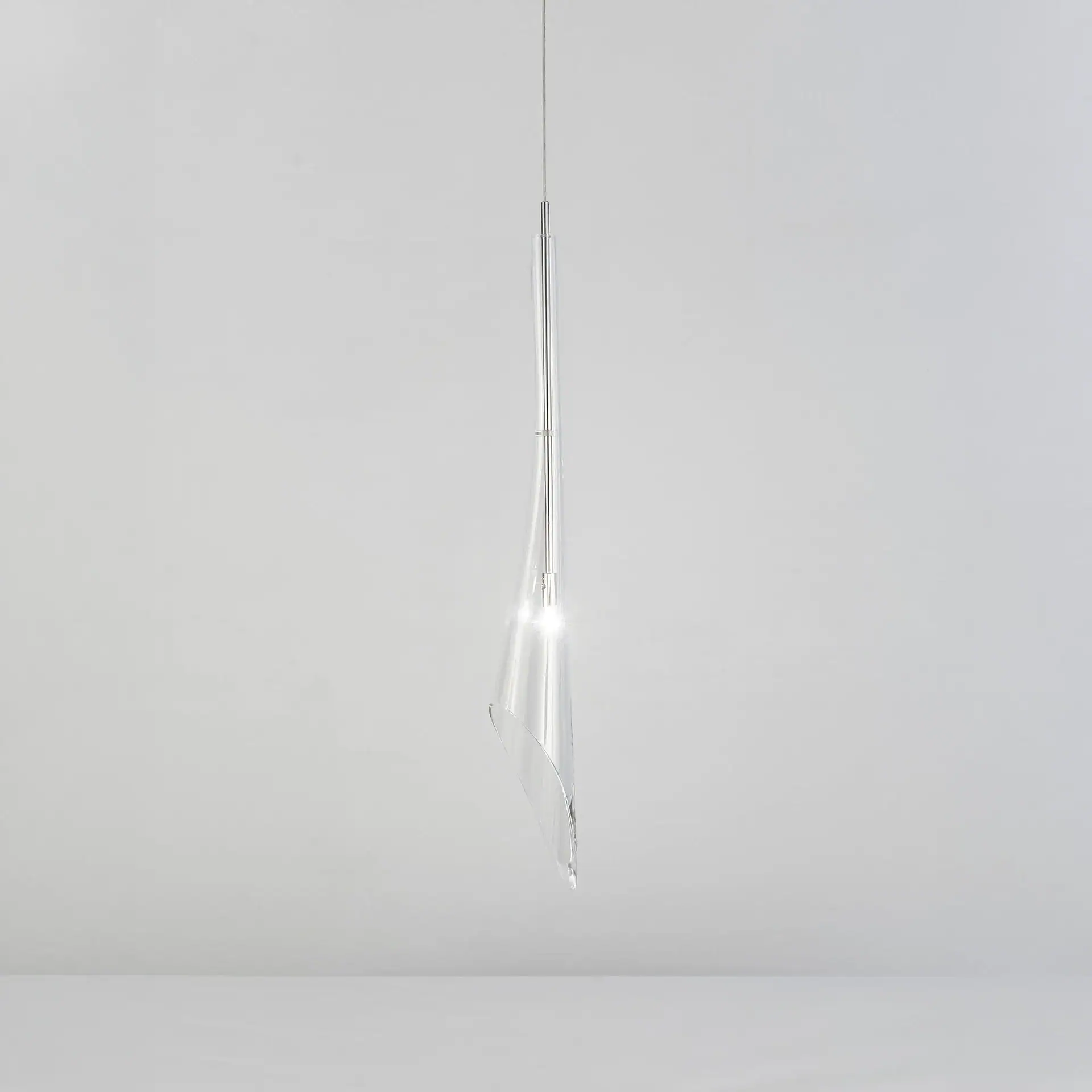 A modern, clear pendant light with a twisted design, suspended by a thin wire, glowing brightly against a light gray background.