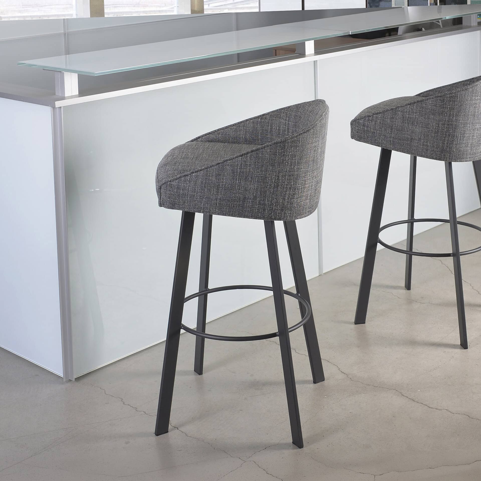 Swivel bar and counter stool with upholstered gray fabric and black wooden legs.