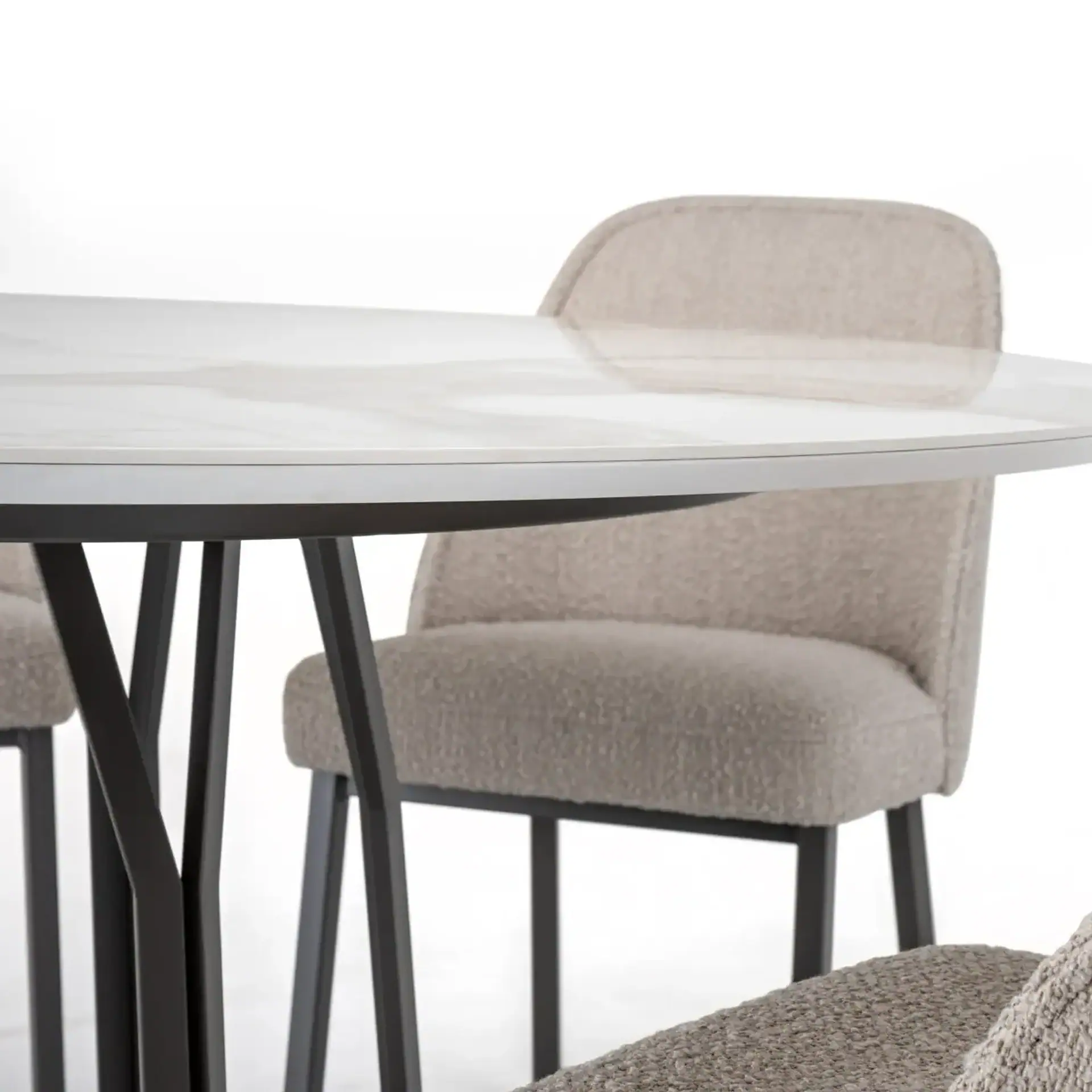 Elegant beige upholstered dining chair with black wooden legs and a sleek round glass table.