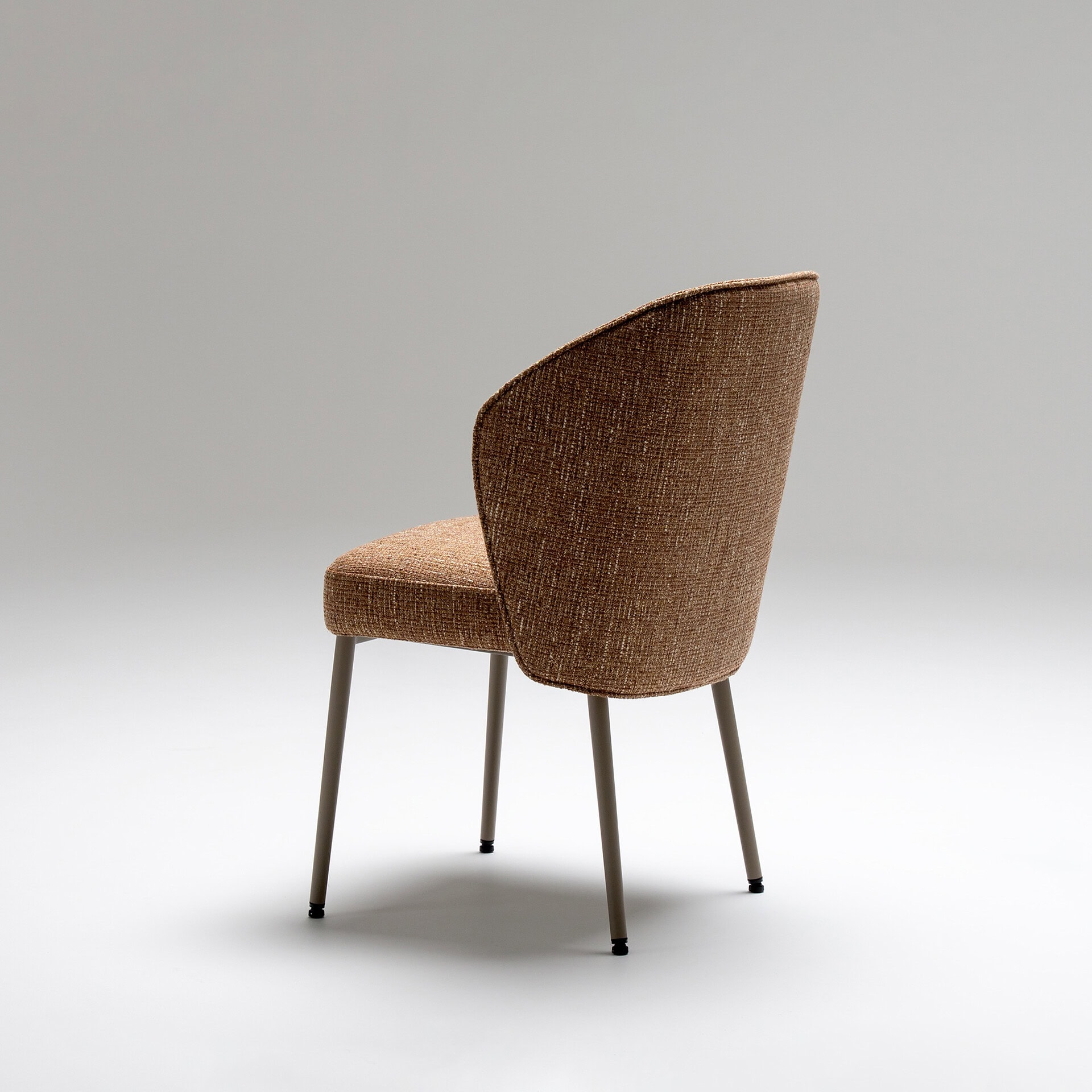 Upholstered Tessa dining armchair with curved backrest and sleek metal legs. Perfect for modern dini.