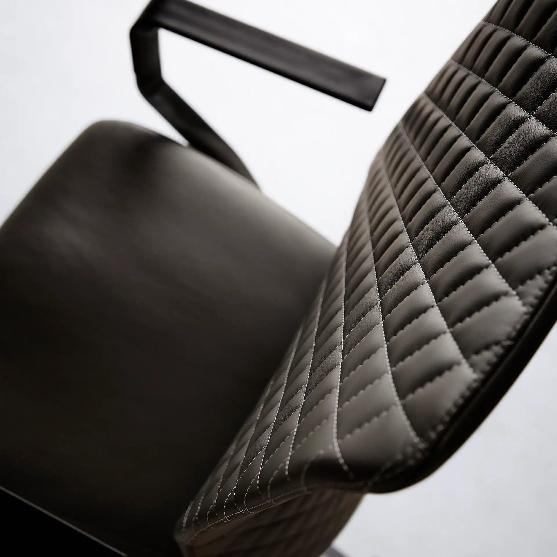 Close-up of black quilted office chair with armrest.