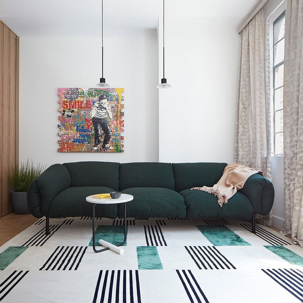 Stylish dark green sofa in contemporary living room with artwork and natural light.