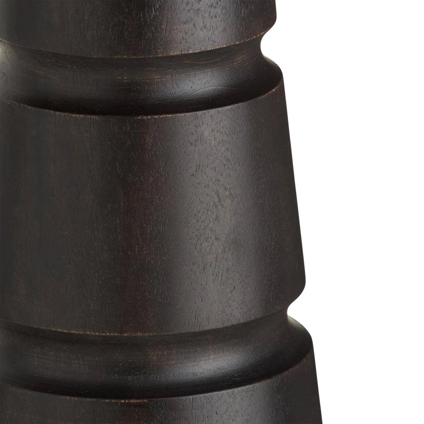 Close-up of a dark brown, sculpted wooden object with carved horizontal bands and concave curves against a white background.