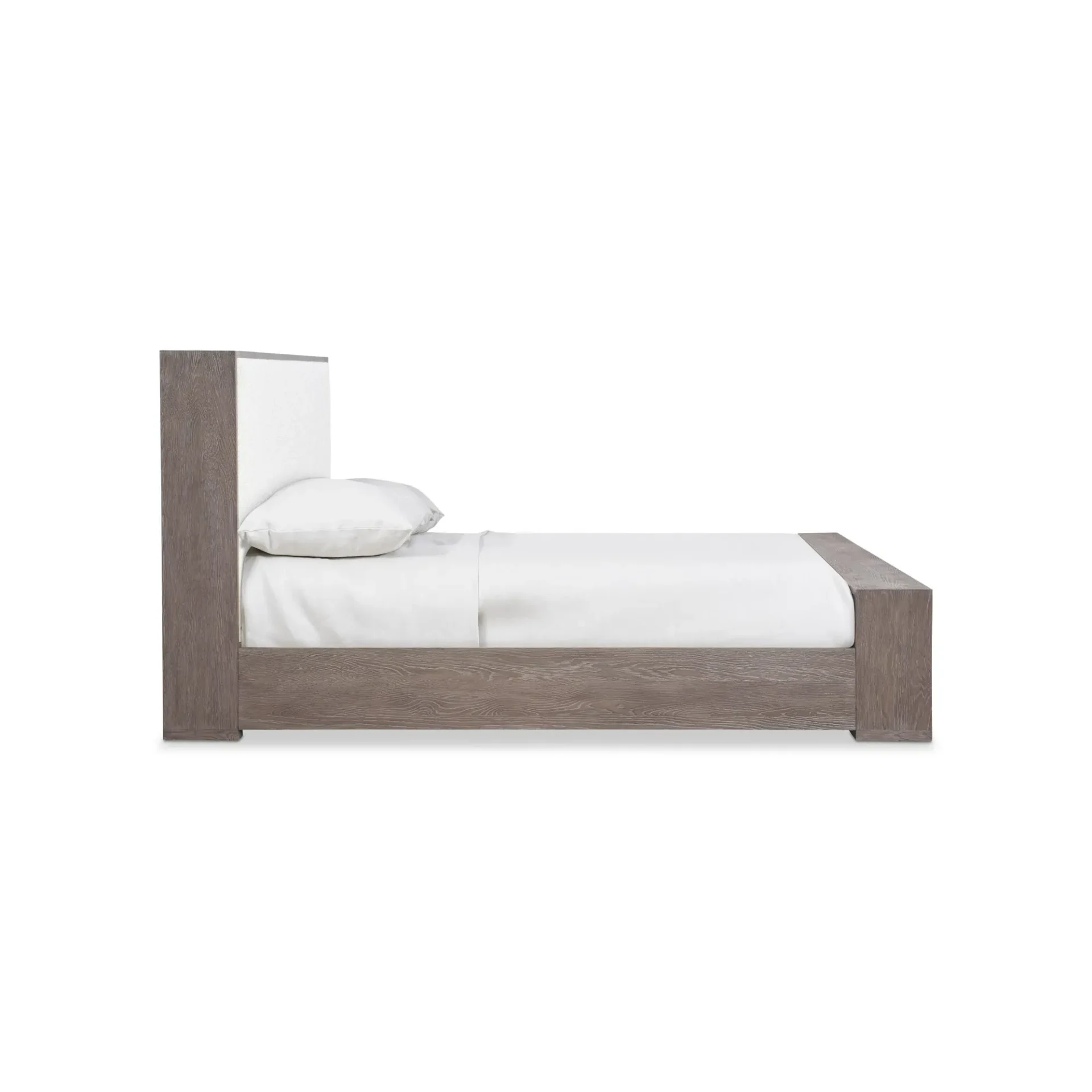 Side view of a bed with a grey wood frame, white upholstered headboard, and white bedding, against a white background.