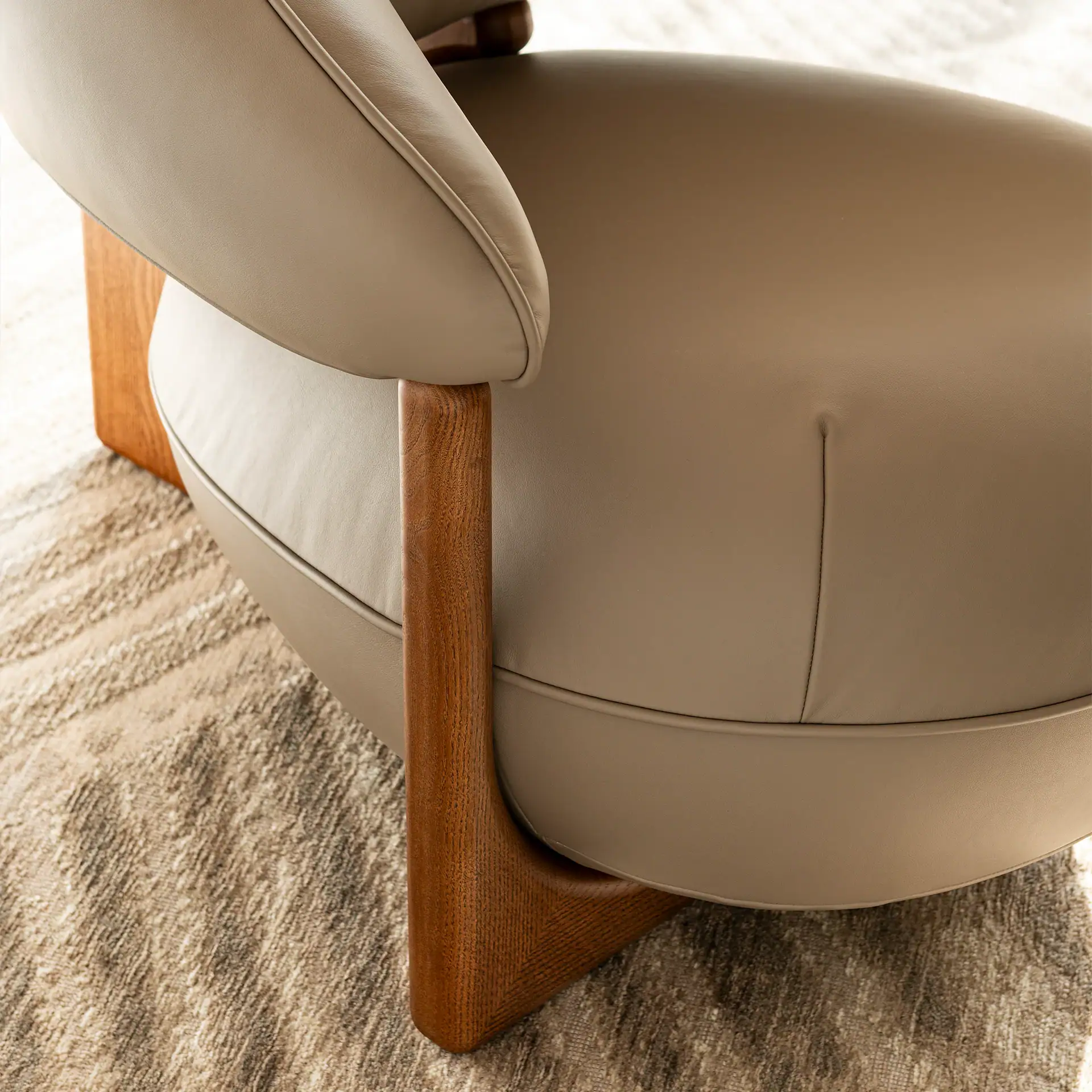 Close-up of the stylish Ruby Lounge Armchair with wooden legs and beige upholstery.