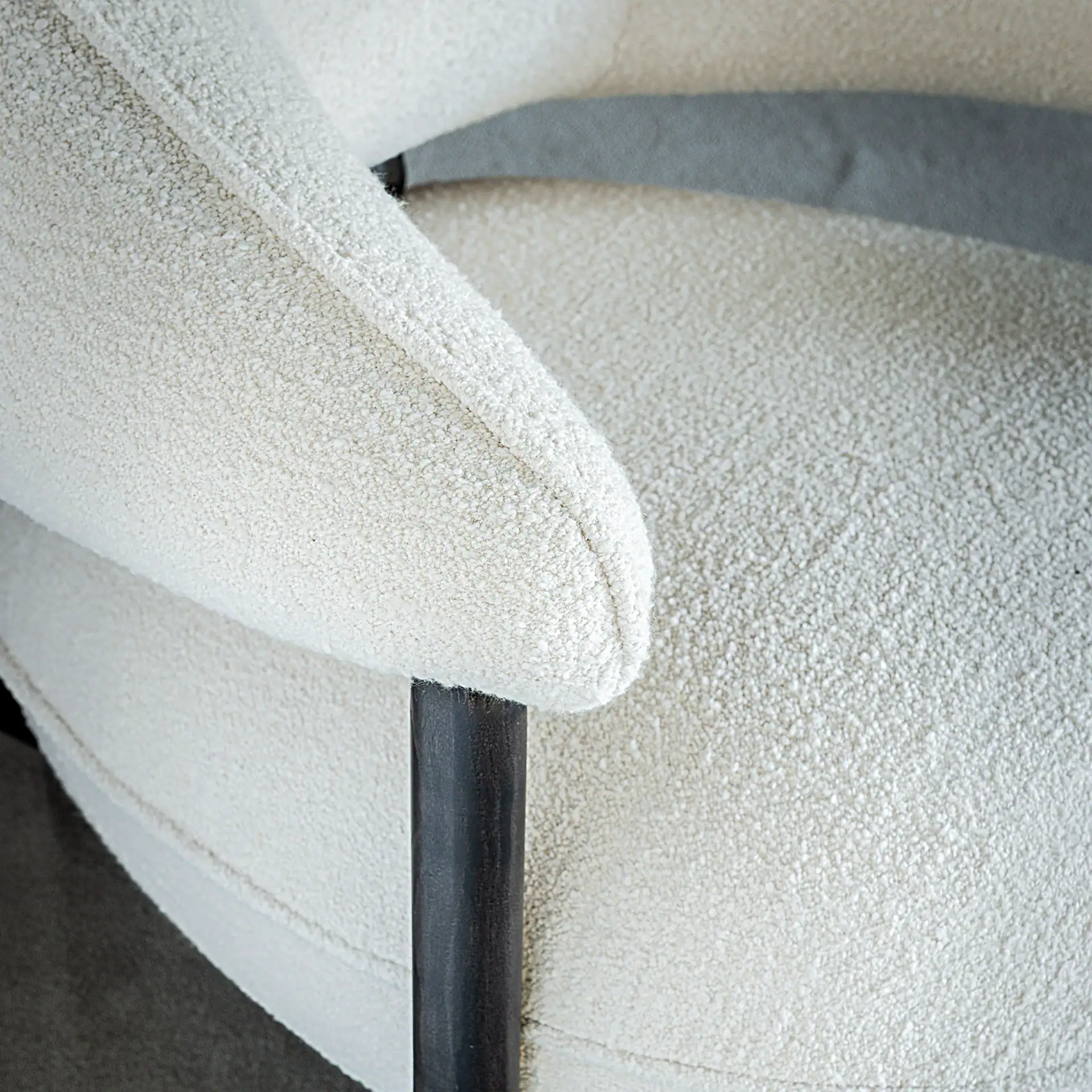 Close-up of the textured fabric and sleek black leg of the Ruby Lounge Armchair.