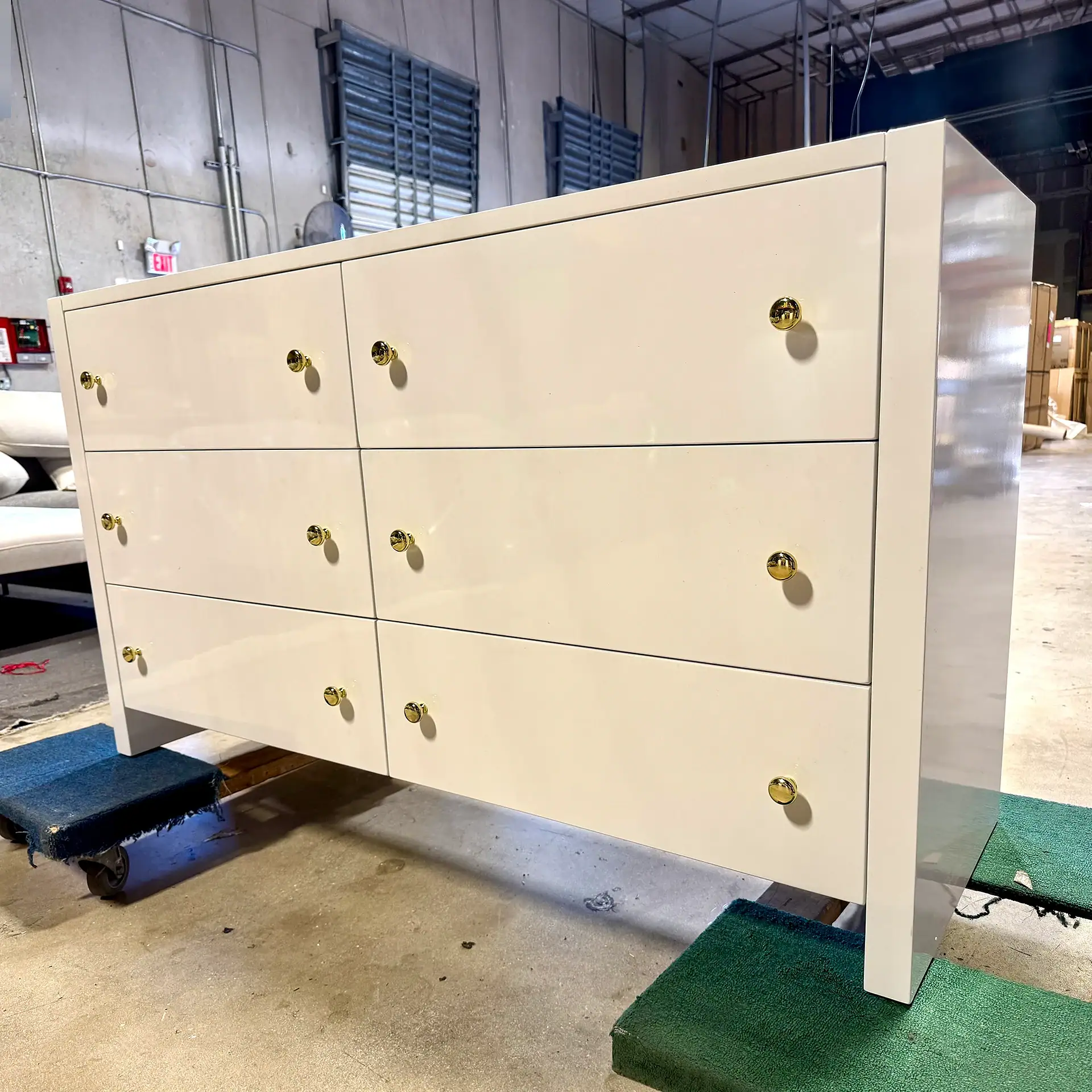 Elegant white six-drawer dresser with gold knobs in industrial setting.