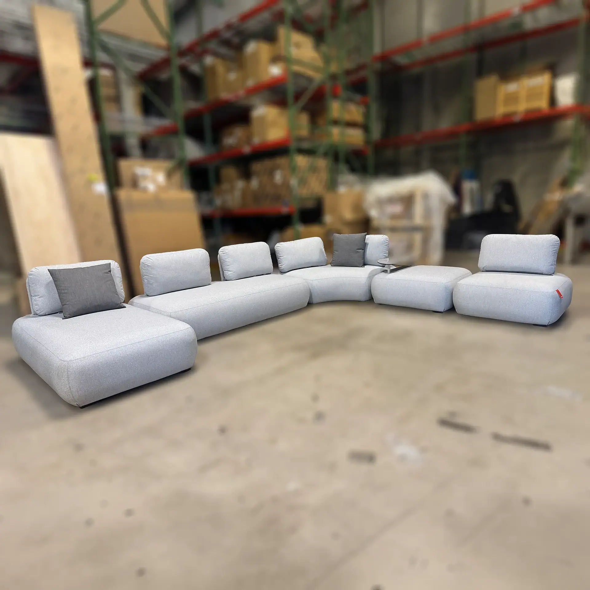 Modern outdoor sectional sofa with light gray cushions and pillows.