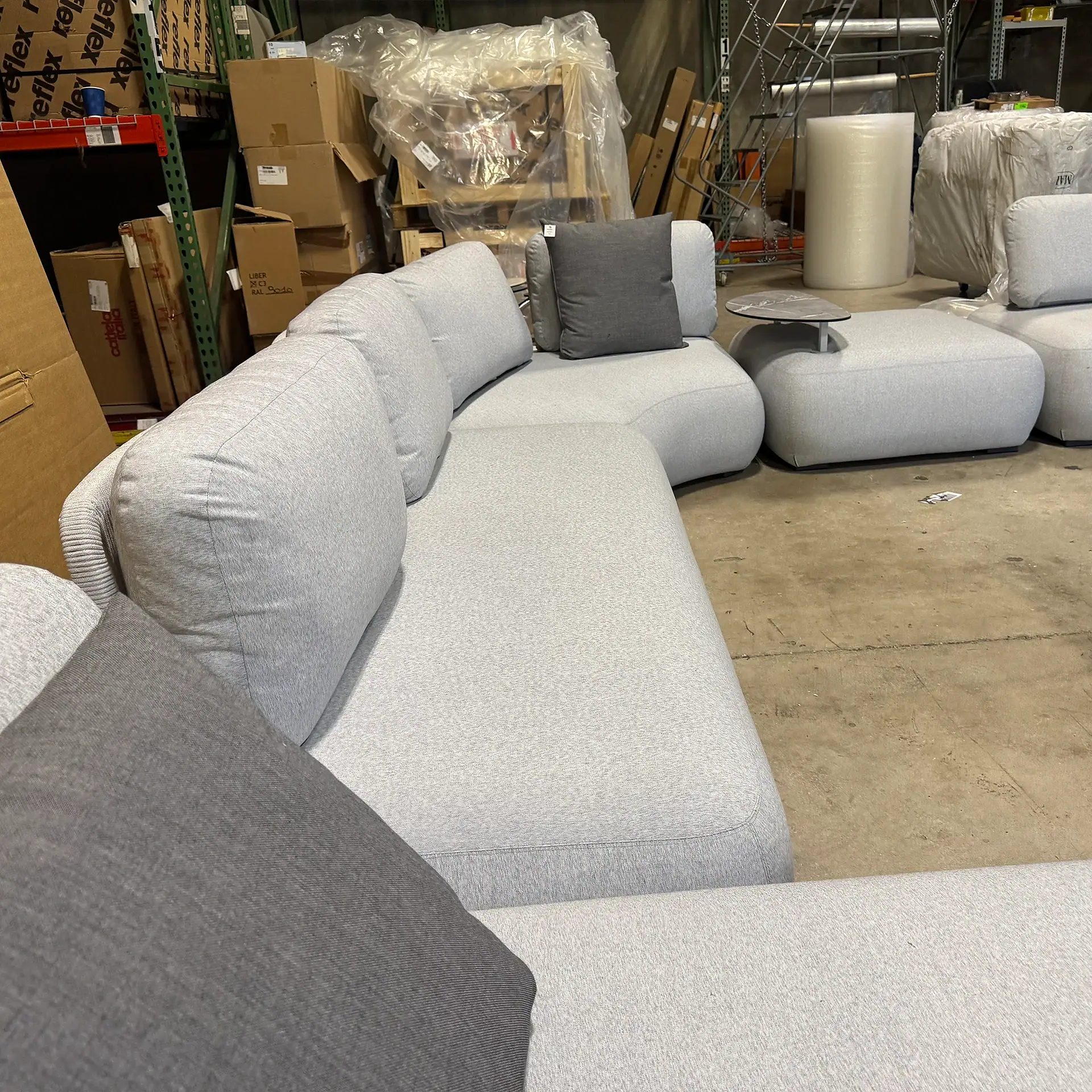Outdoor sectional sofa with gray cushions in warehouse setting.