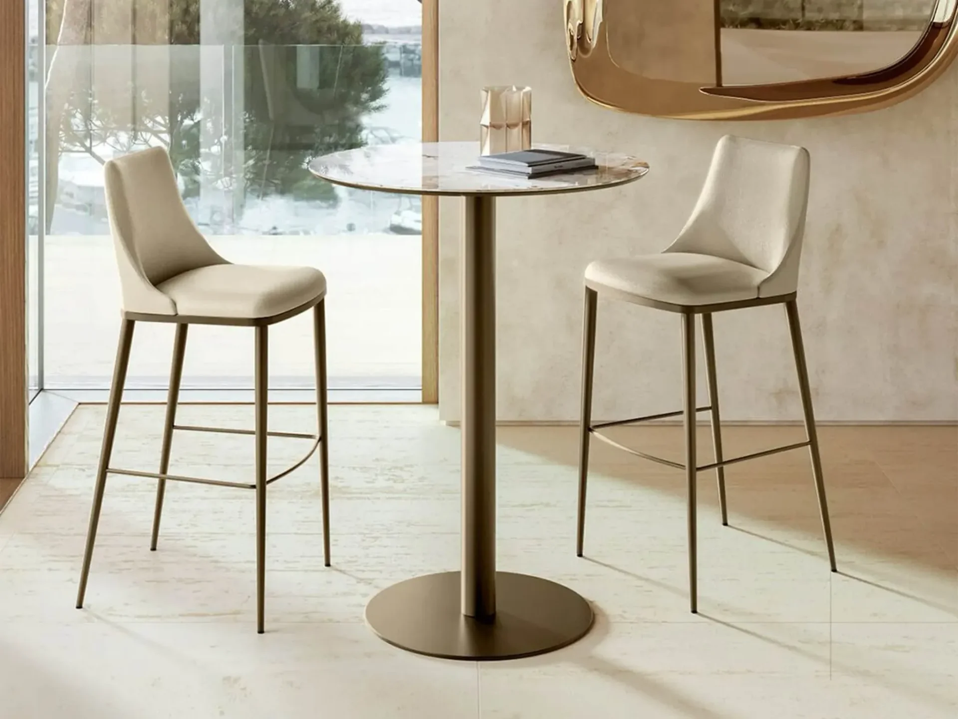 Two beige upholstered bar stools and a round marble high-top table next to a large window.