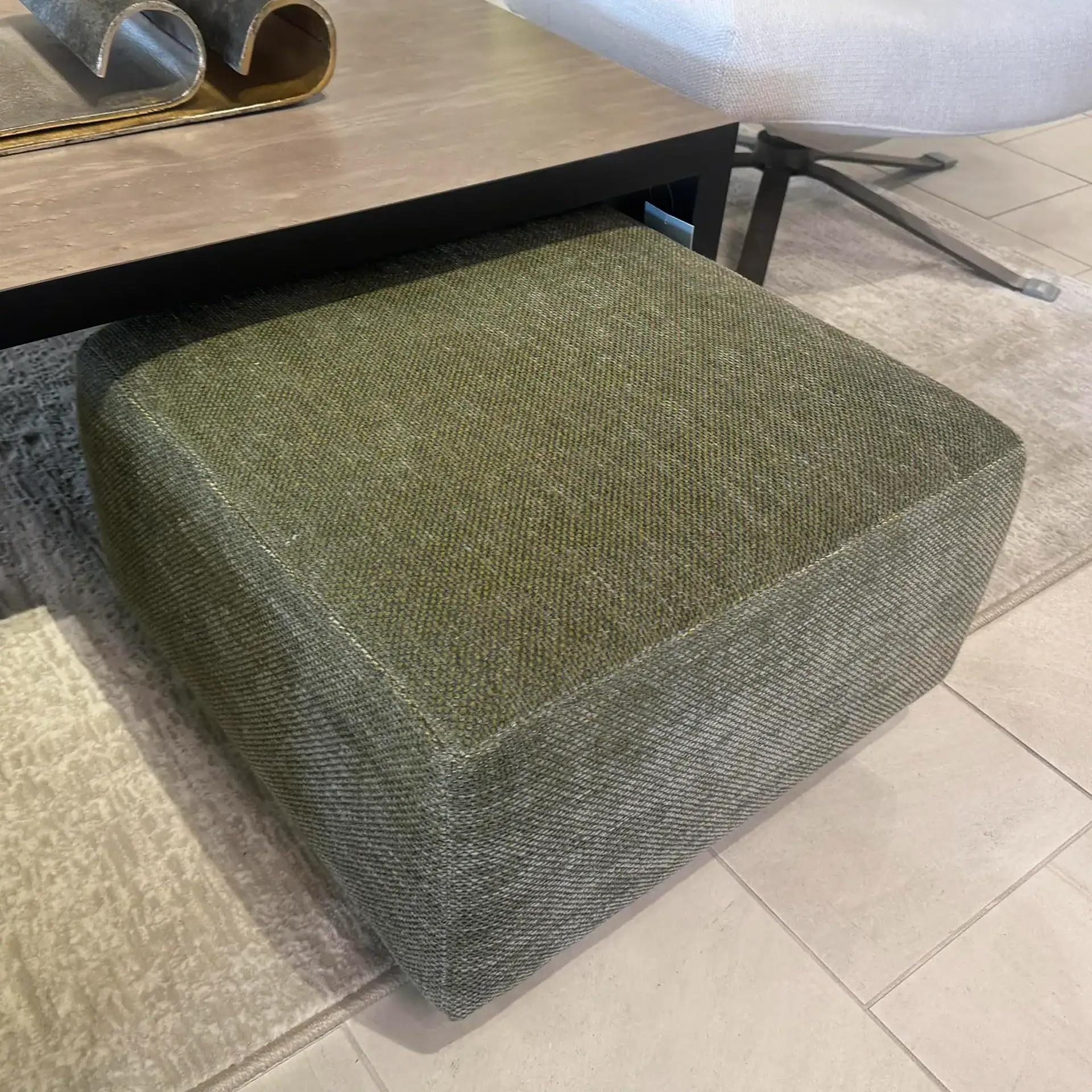 Green fabric pouf with a contemporary design, perfect for stylish living spaces.