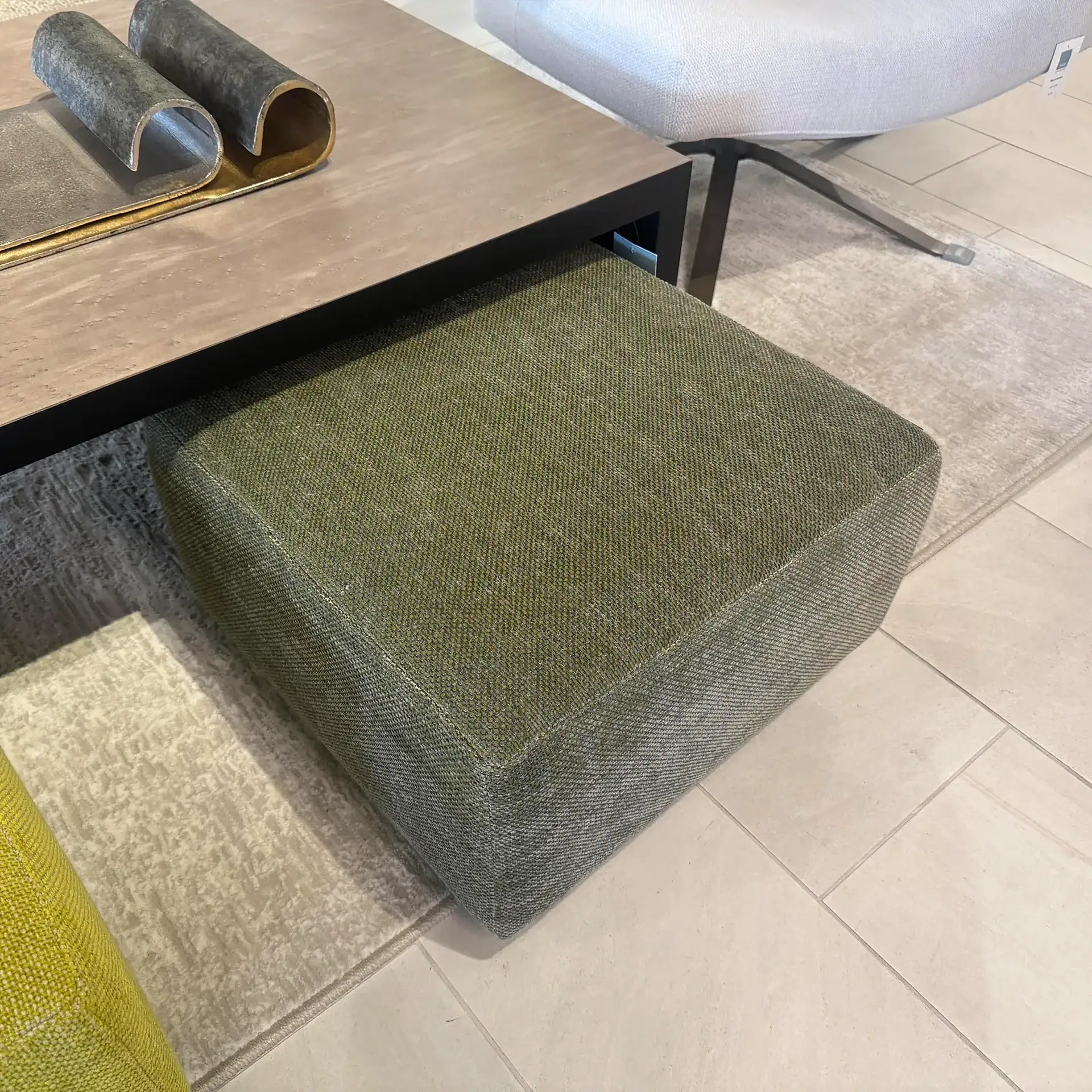 Pouf ottoman with textured green fabric, ideal for contemporary living spaces.
