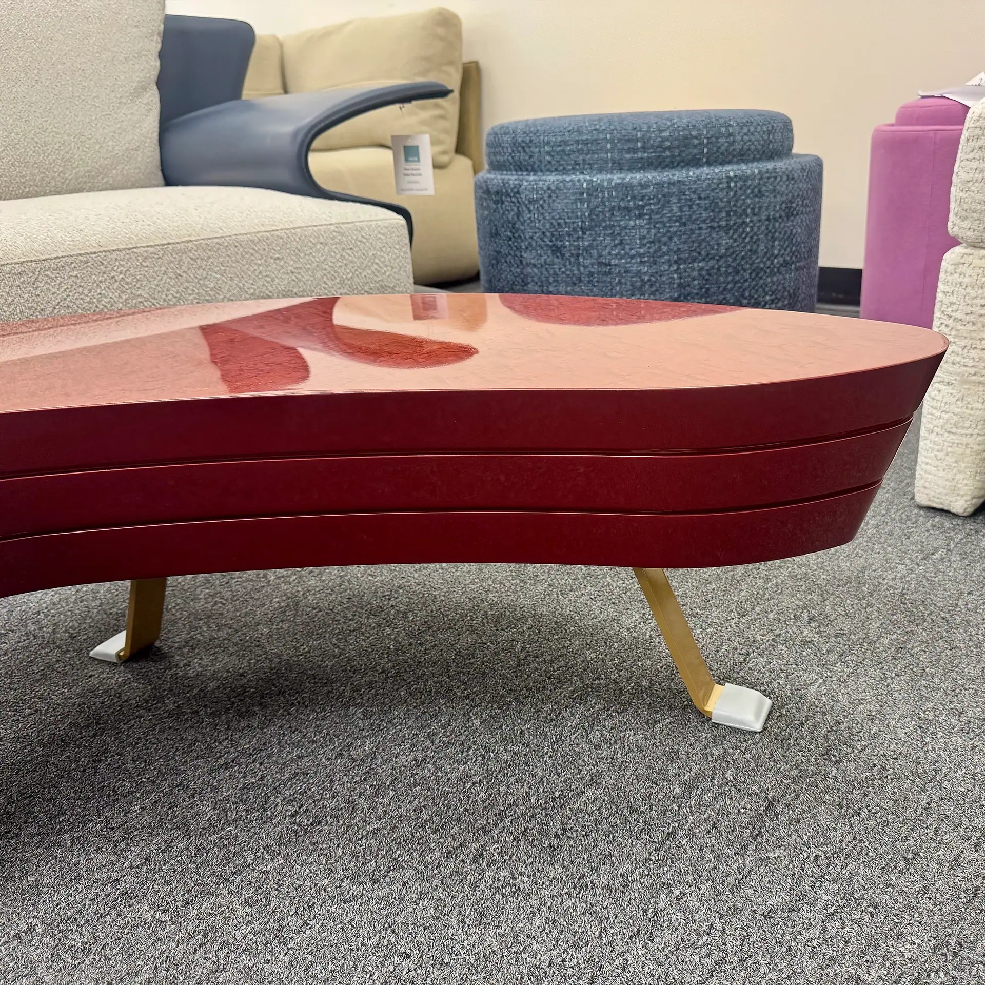 Modern red coffee table with curved design and gold legs in living room.