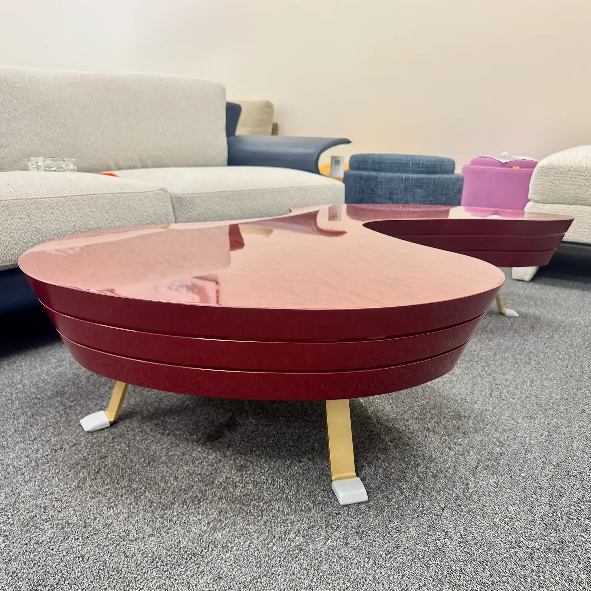 Modern red coffee table with gold legs in a furniture showroom.