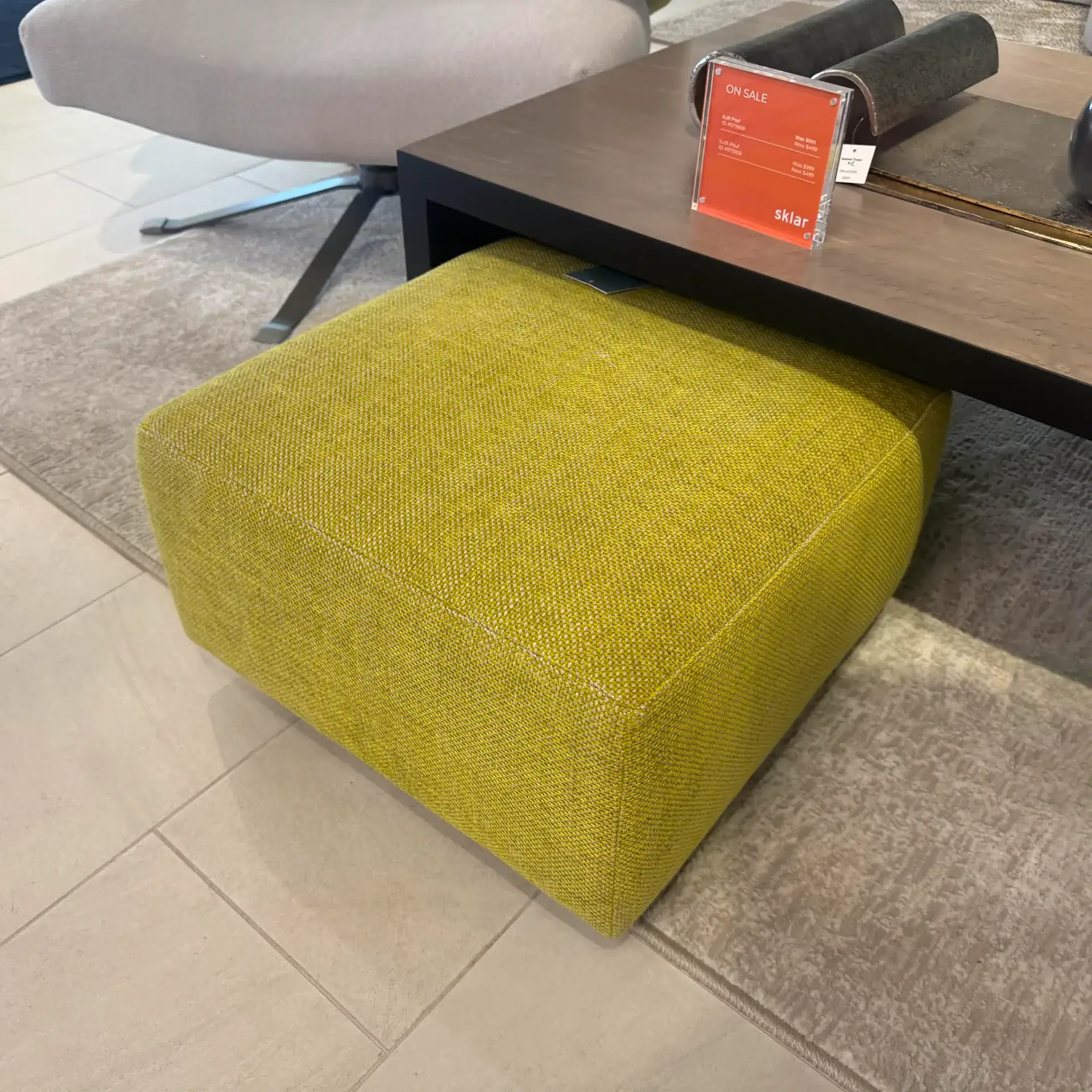 Green fabric pouf with a contemporary design, perfect for living room decor.