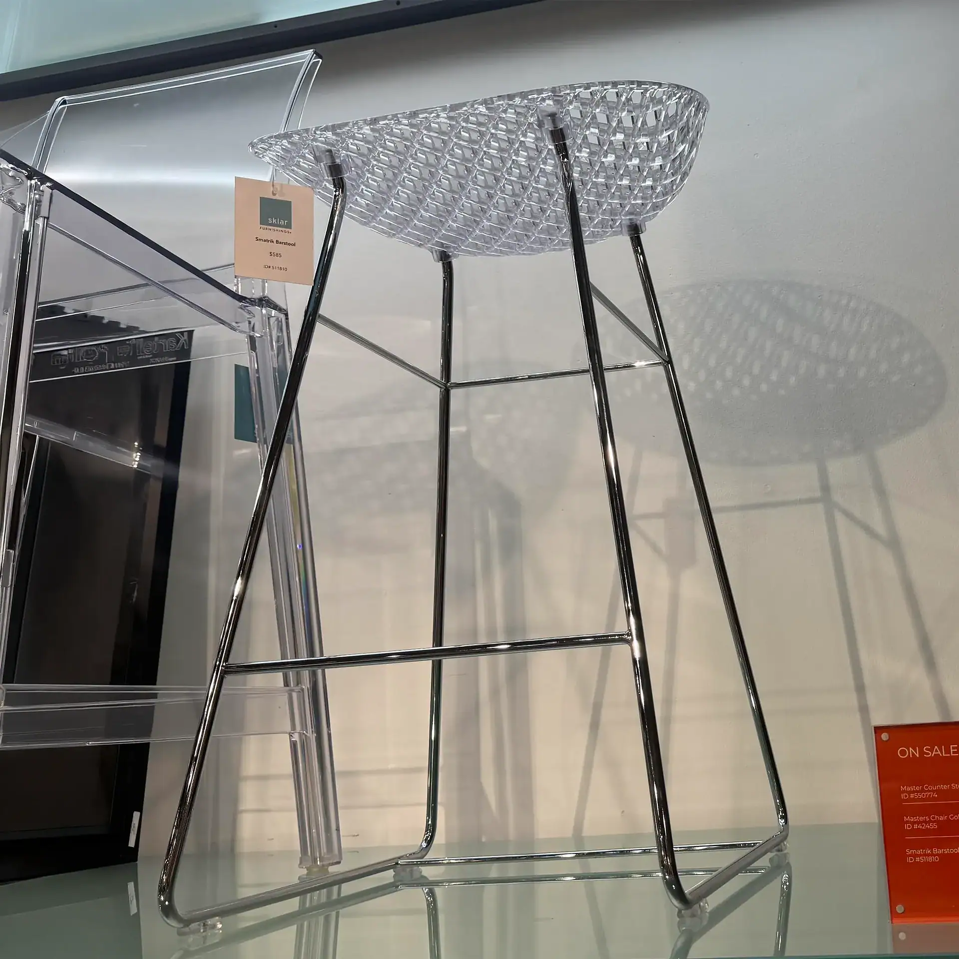 Modern Kartell Smarik barstool with transparent seat and sleek metal legs.