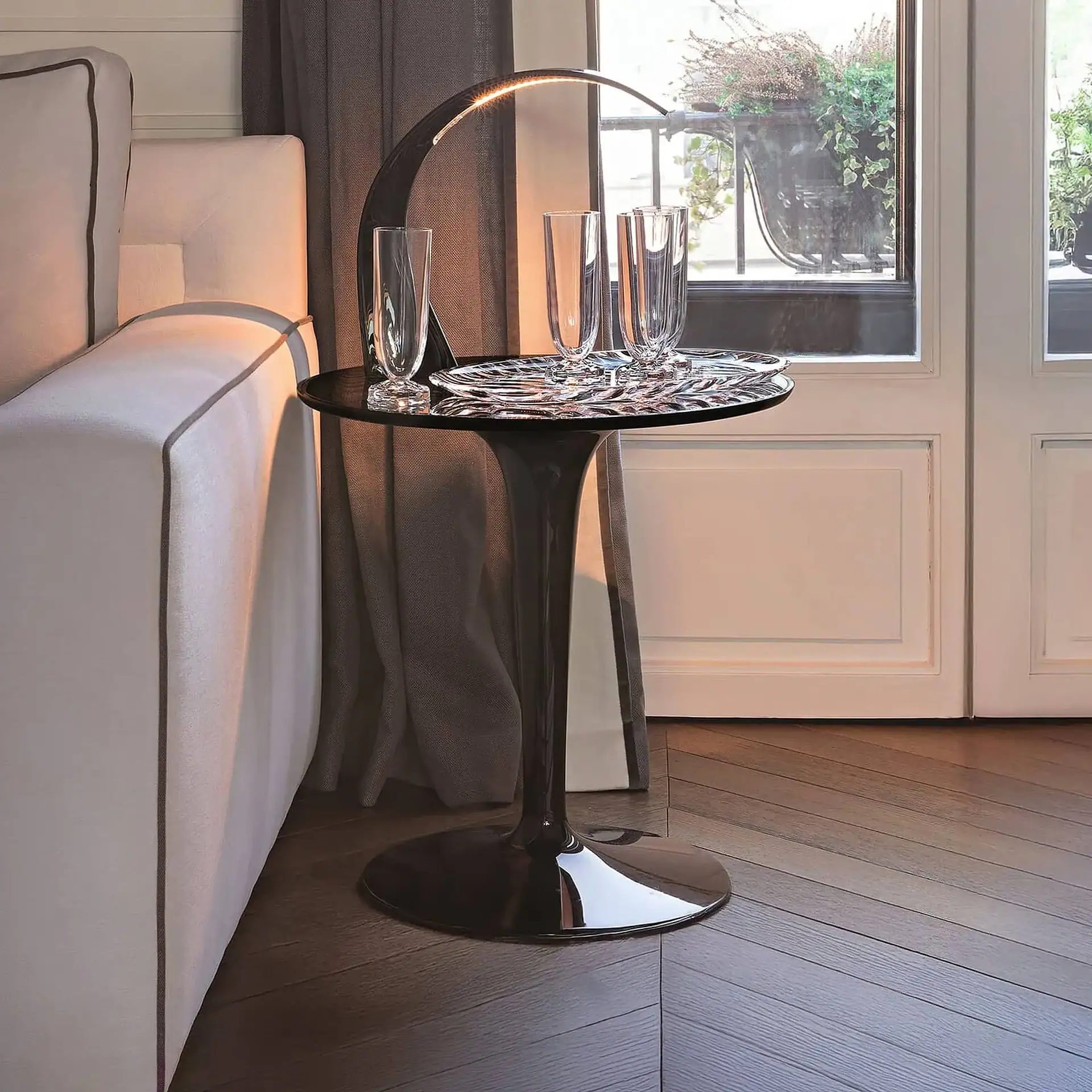 Modern Kartell TipTop side table with glassware in stylish living room.