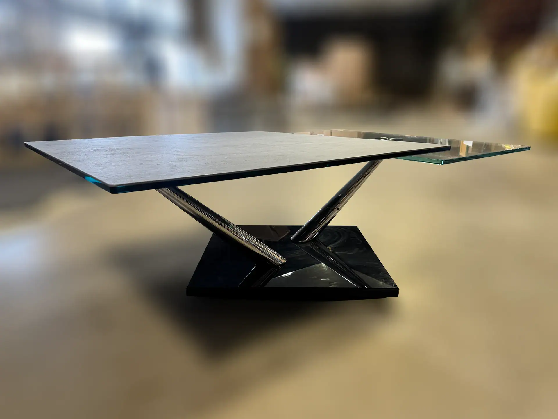 Modern cocktail table with glass top and unique base design.