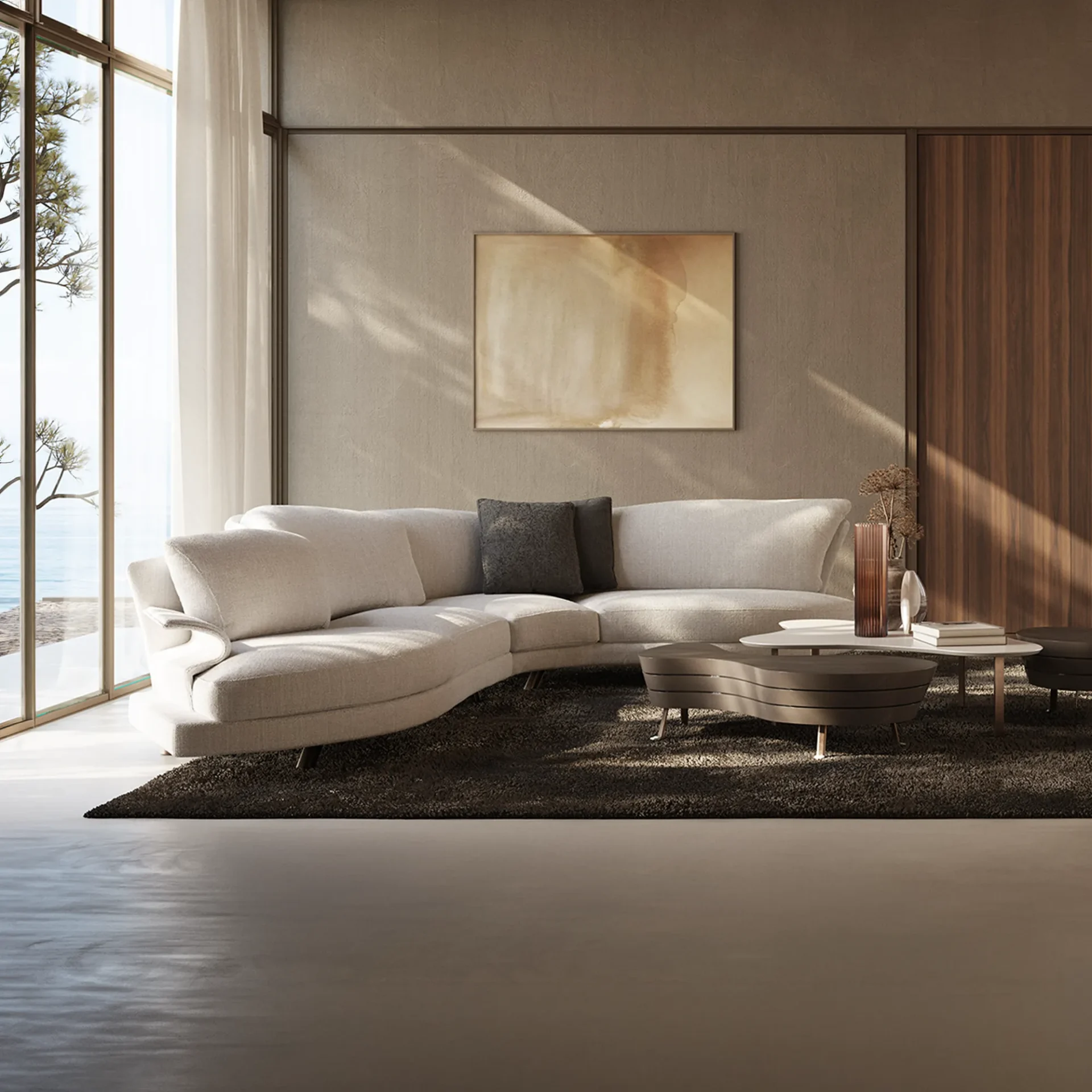 A modern living room with a curved light-colored sofa, dark coffee tables, and a large window overlooking the ocean.