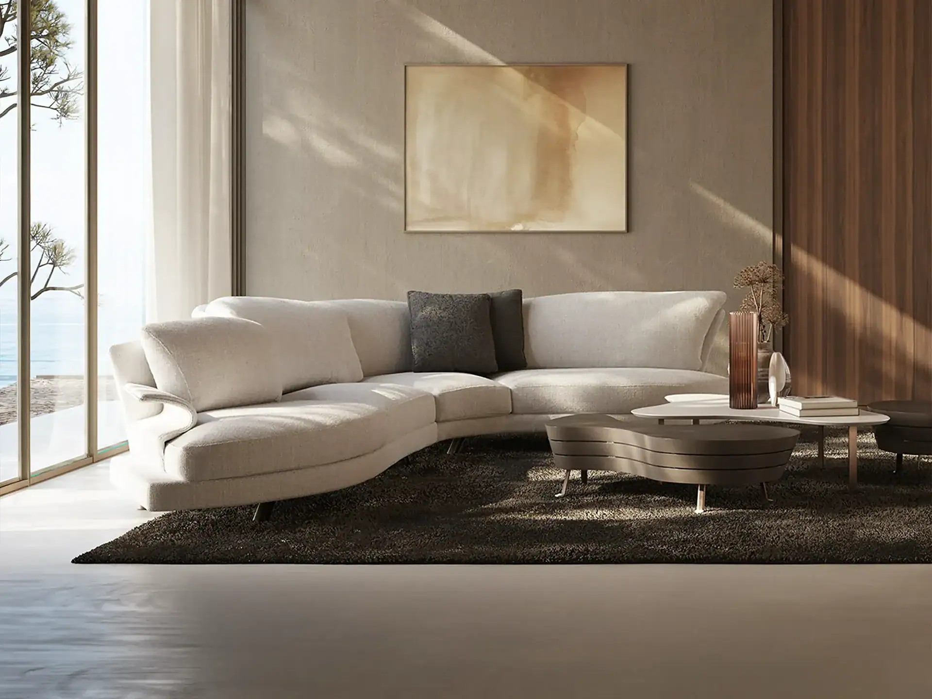 A modern living room with a light curved sectional sofa, dark rug, abstract art, and a large window overlooking water and trees.