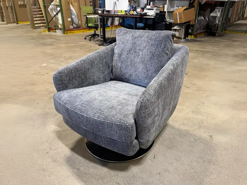 Modern grey swivel lounge chair with plush cushioning and rounded armrests.