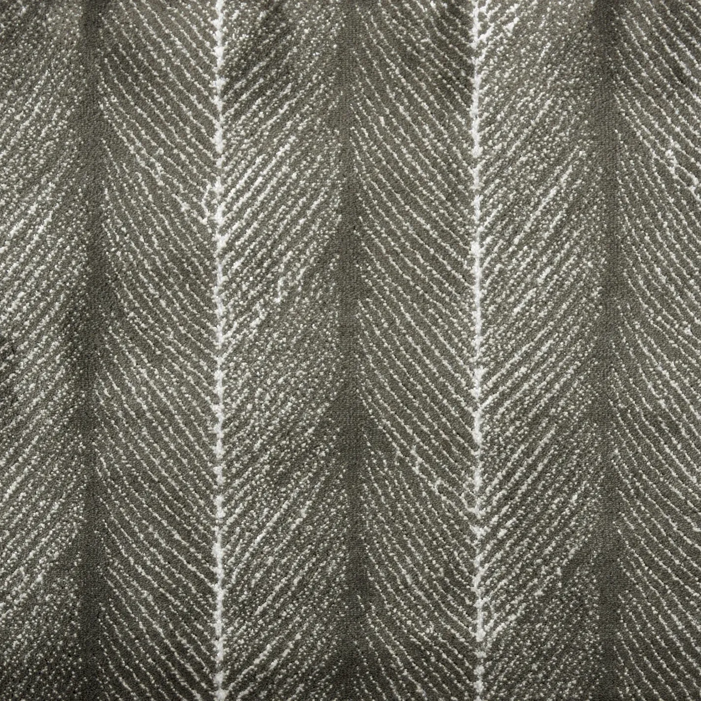 Close-up of a dark grey fabric with a textured light grey chevron or herringbone pattern.
