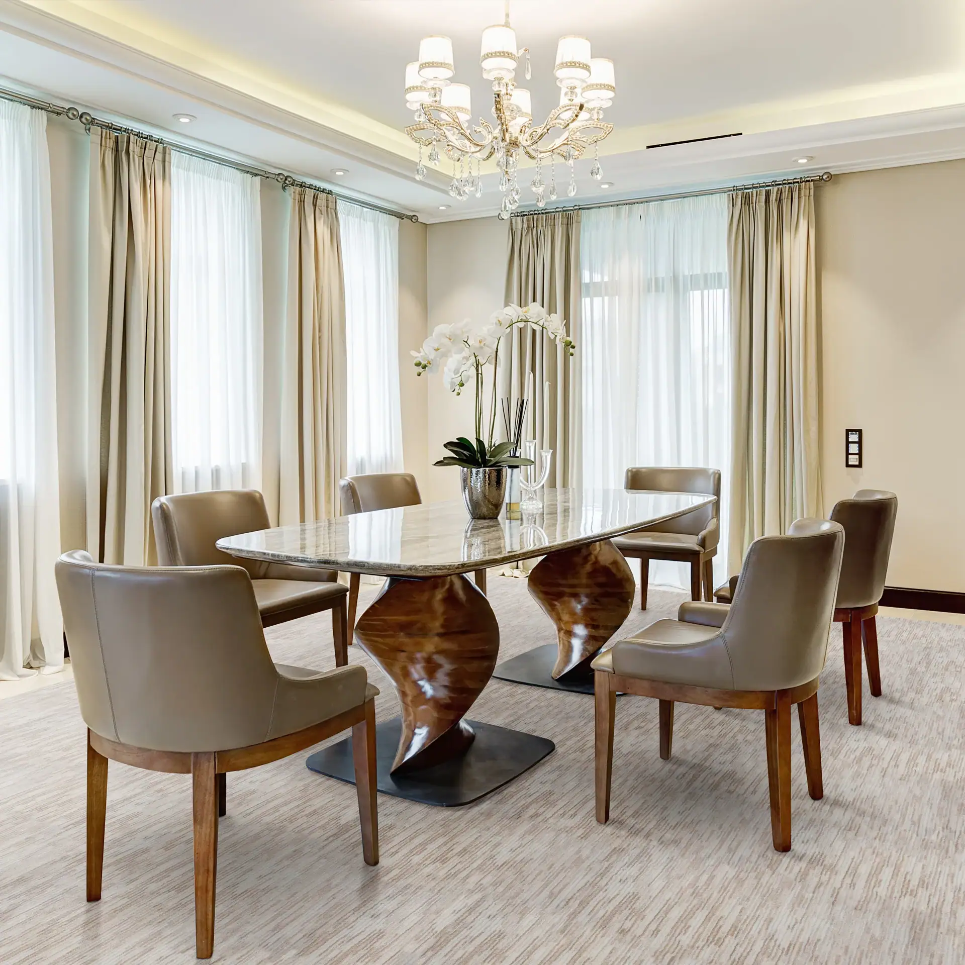 Modern dining room with elegant table, chairs, and chandelier in a bright, stylish space.