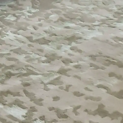 Beach sand with footprints and textured surface.