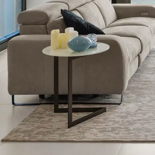 Beige sofa with side table, candles, and decorative vases in contemporary living room setting.