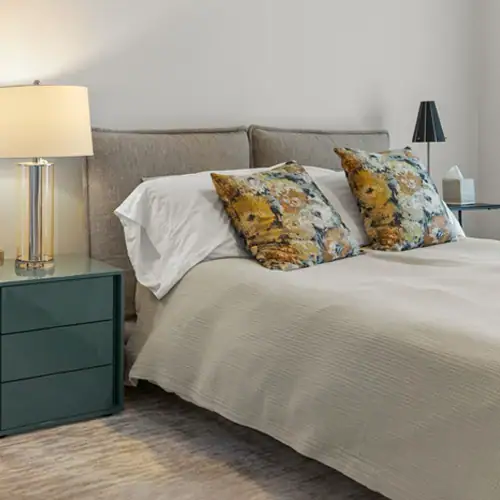 Stylish bedroom featuring a plush bed, decorative pillows, and contemporary nightstands with lamps.